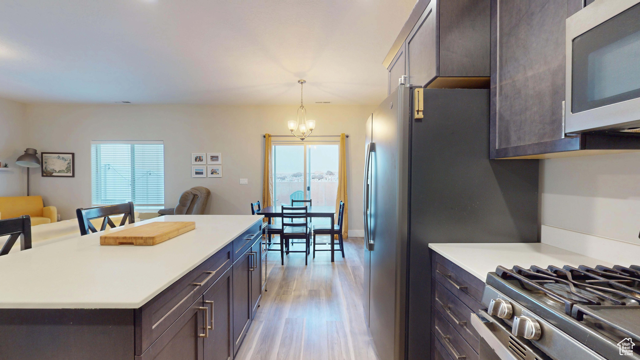 Kitchen featuring stainless steel appliances, plenty of natural light, dark brown cabinetry, and decorative light fixtures