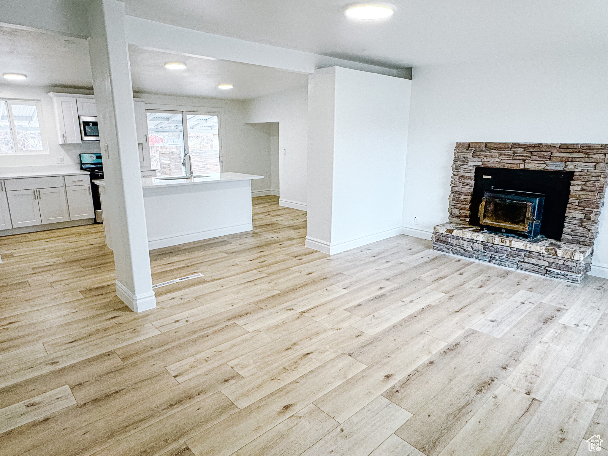 Unfurnished living room featuring a healthy amount of sunlight, sink, and light wood-type flooring