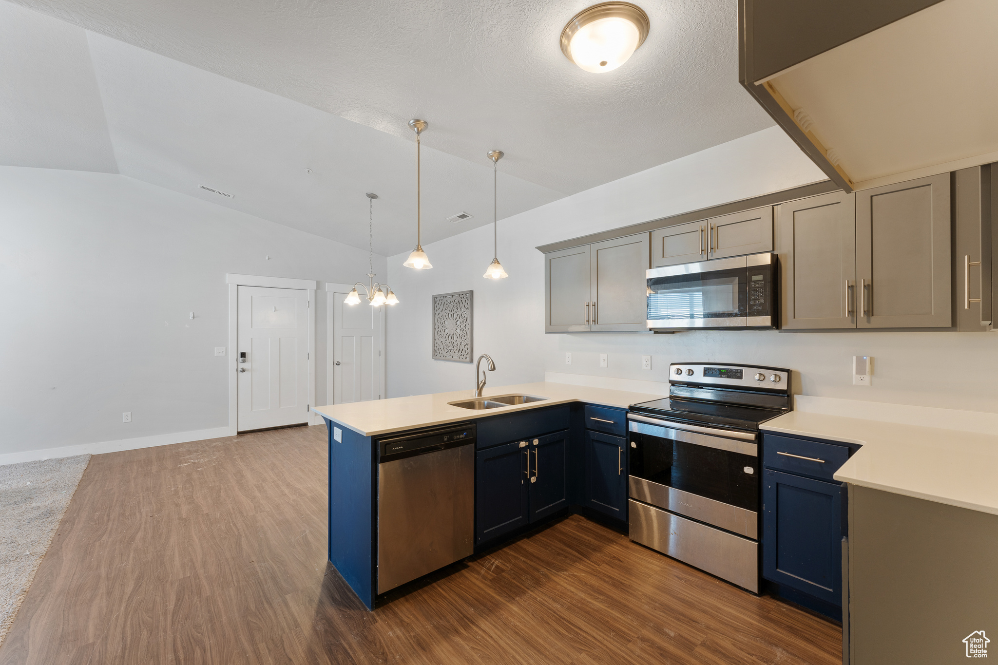 Kitchen with sink, dark hardwood / wood-style flooring, kitchen peninsula, pendant lighting, and stainless steel appliances