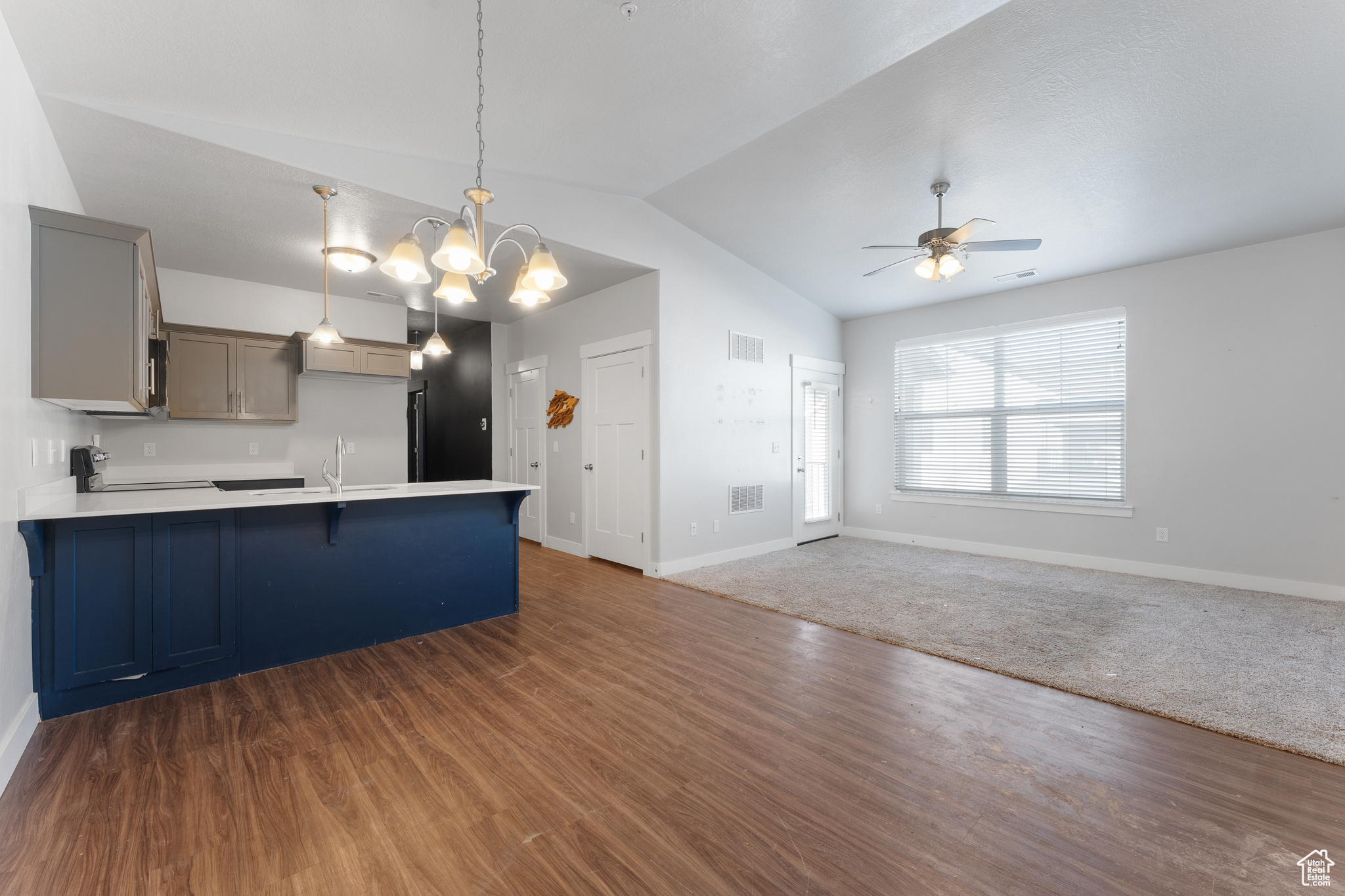 Kitchen with ceiling fan with notable chandelier, sink, gray cabinetry, hanging light fixtures, and dark wood-type flooring