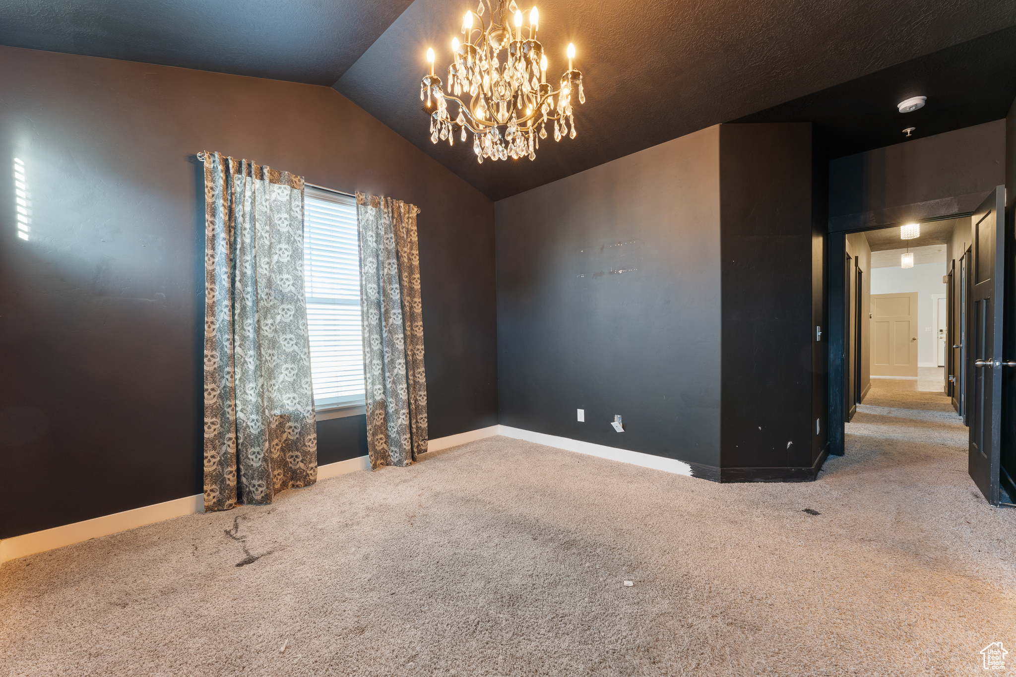 Unfurnished room featuring lofted ceiling, carpet floors, and an inviting chandelier