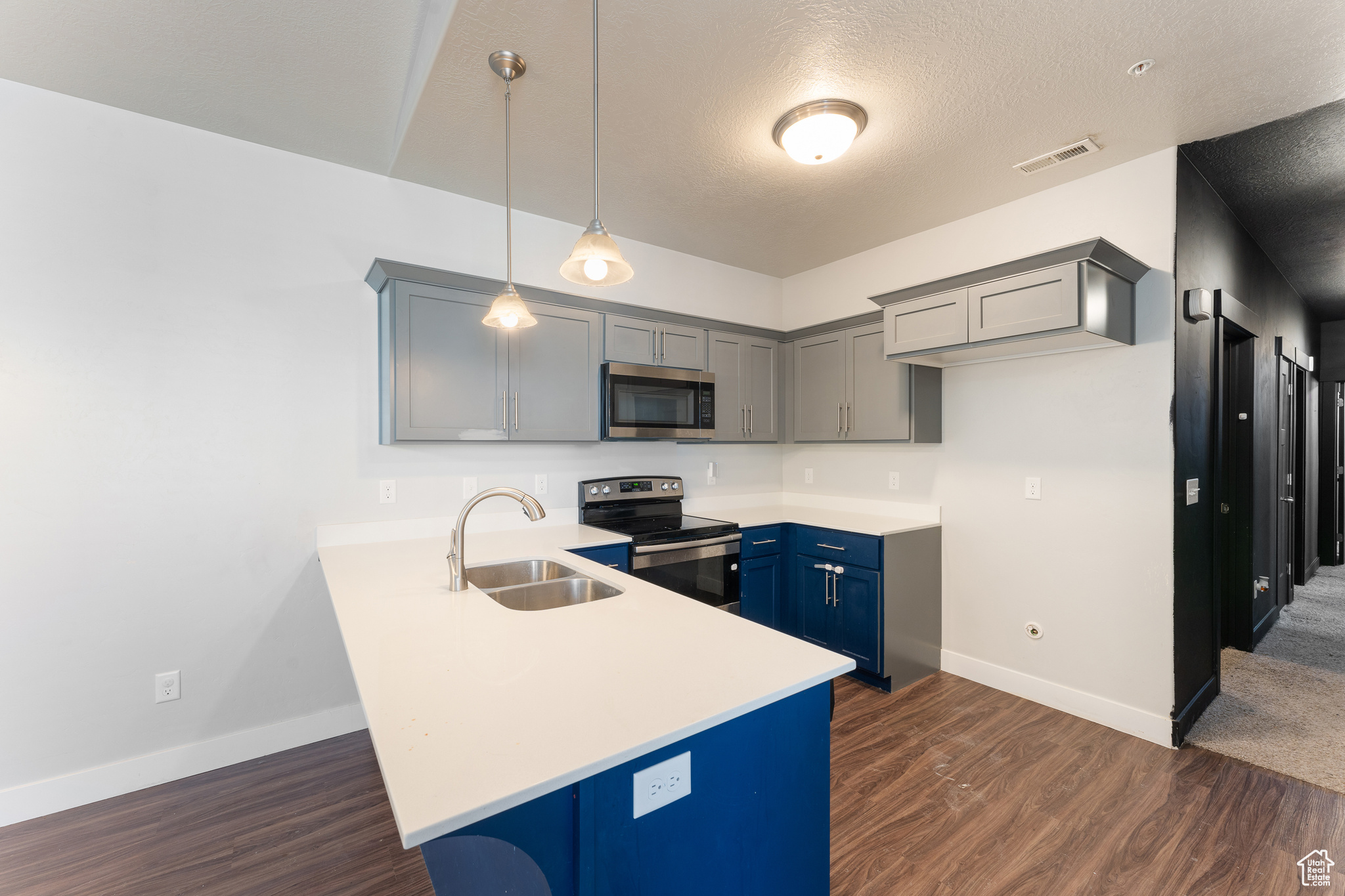 Kitchen featuring a breakfast bar, sink, kitchen peninsula, pendant lighting, and stainless steel appliances