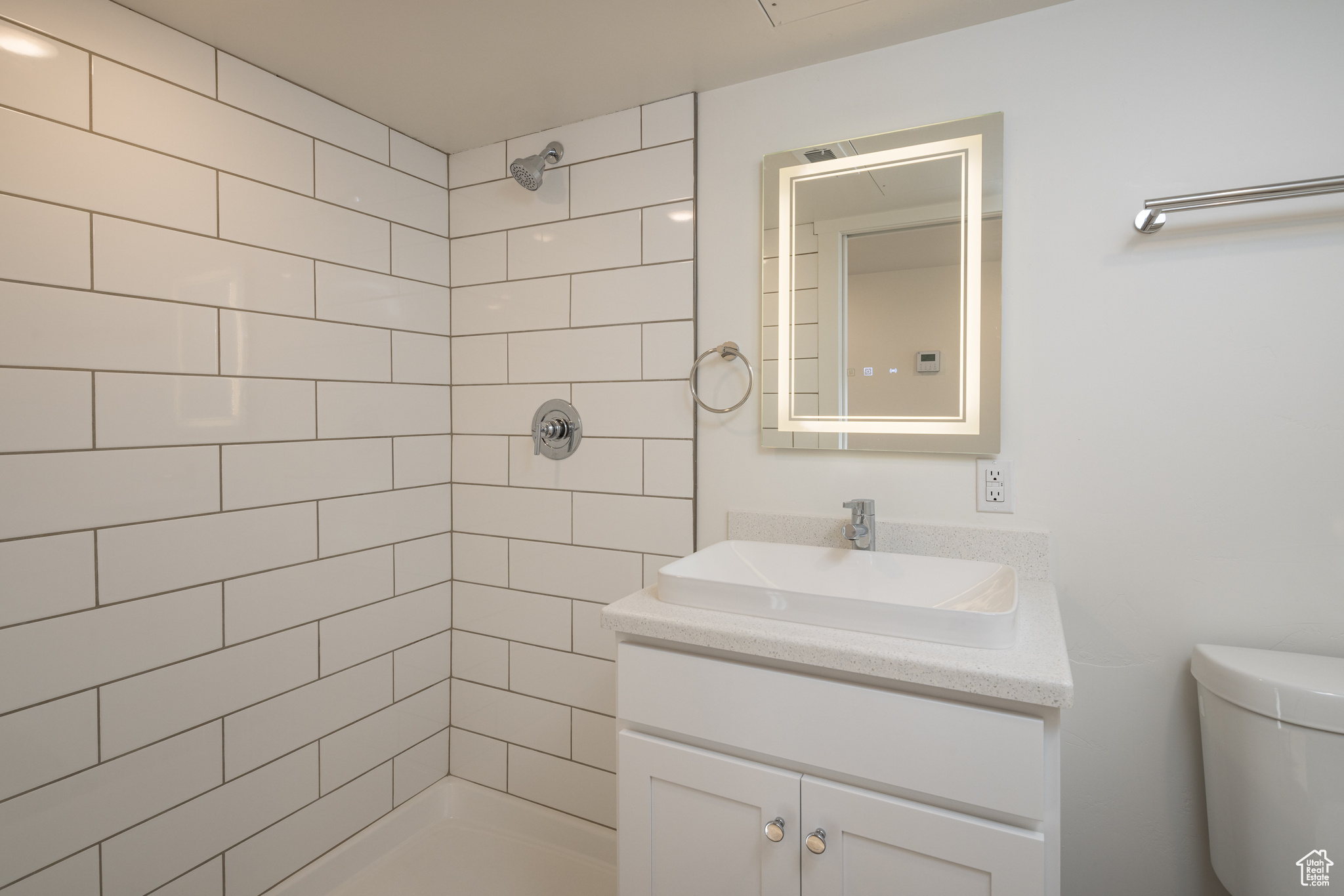 Bathroom featuring vanity, toilet, and a tile shower