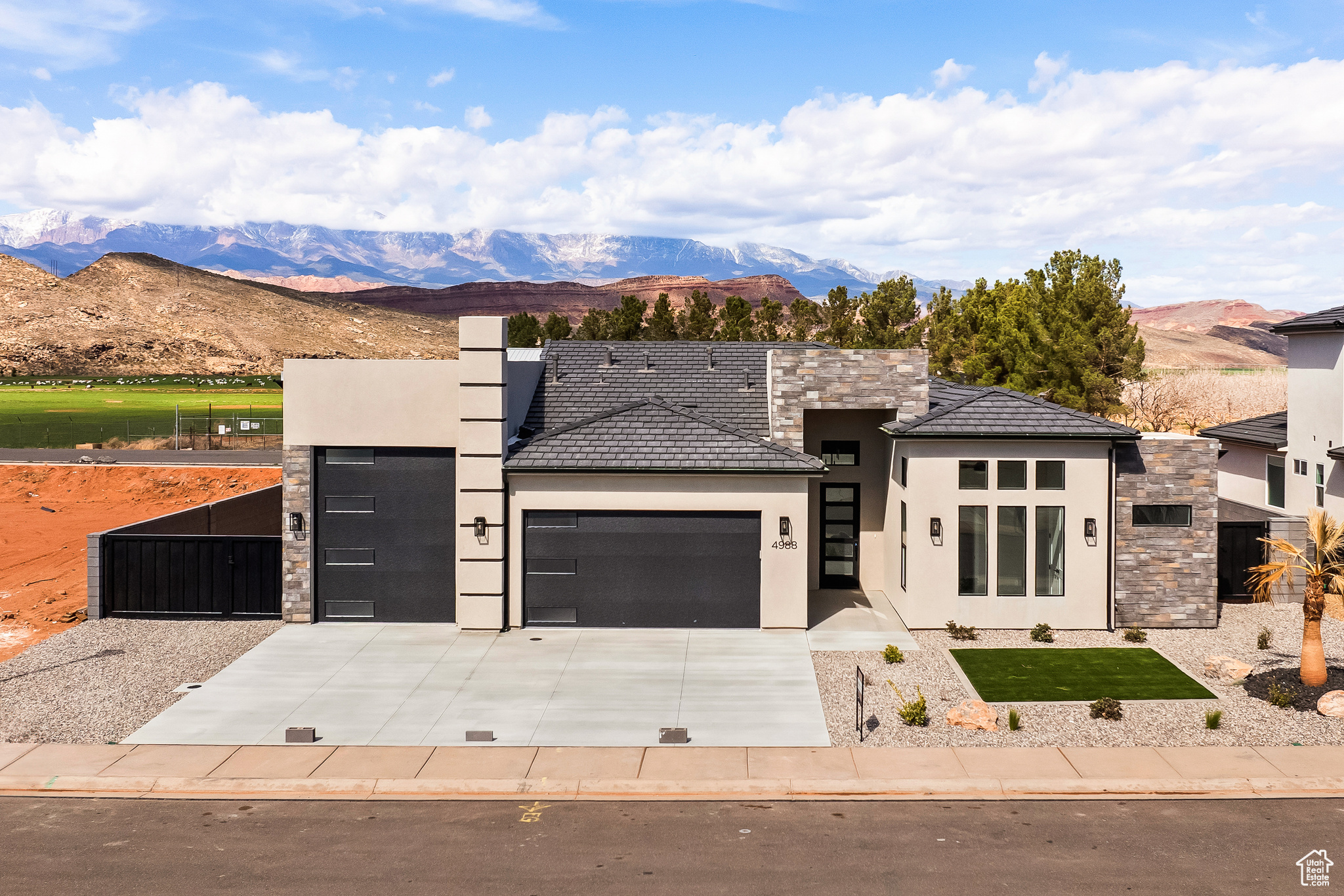 View of front of home with an attached garage, stucco siding, driveway, a mountain view, and a gate