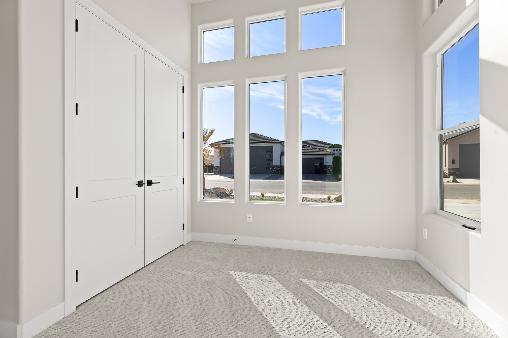 Unfurnished bedroom featuring a towering ceiling, light colored carpet, baseboards, and a closet