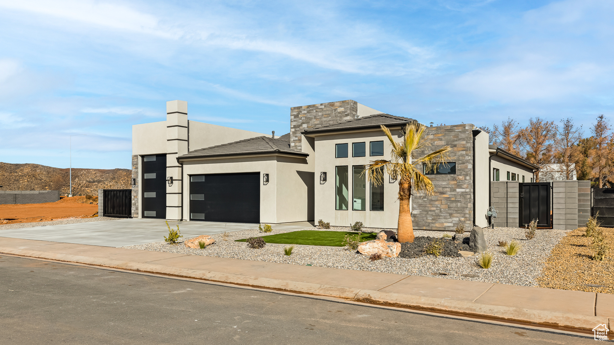 View of front facade with stone siding, concrete driveway, a garage, and fence