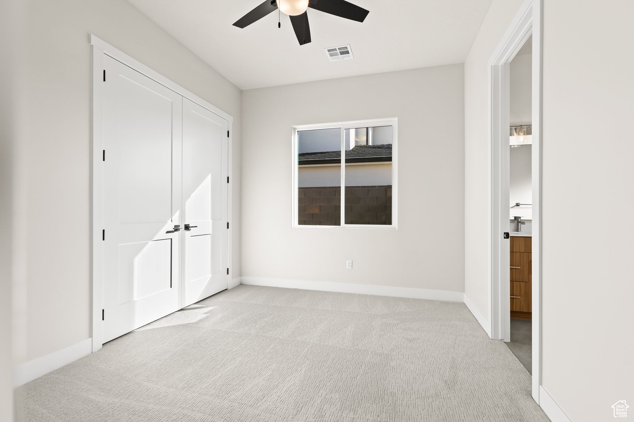 Unfurnished bedroom featuring light carpet, visible vents, a ceiling fan, and baseboards