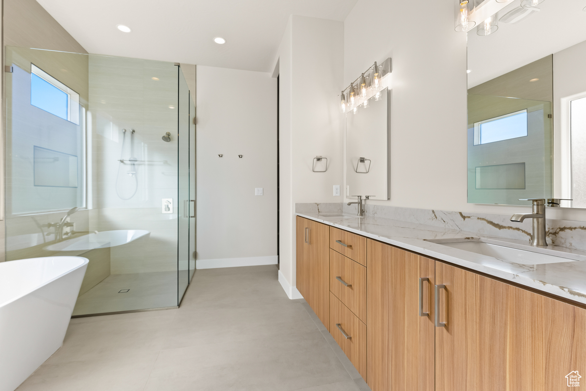 Bathroom featuring a freestanding bath, double vanity, recessed lighting, a stall shower, and a sink
