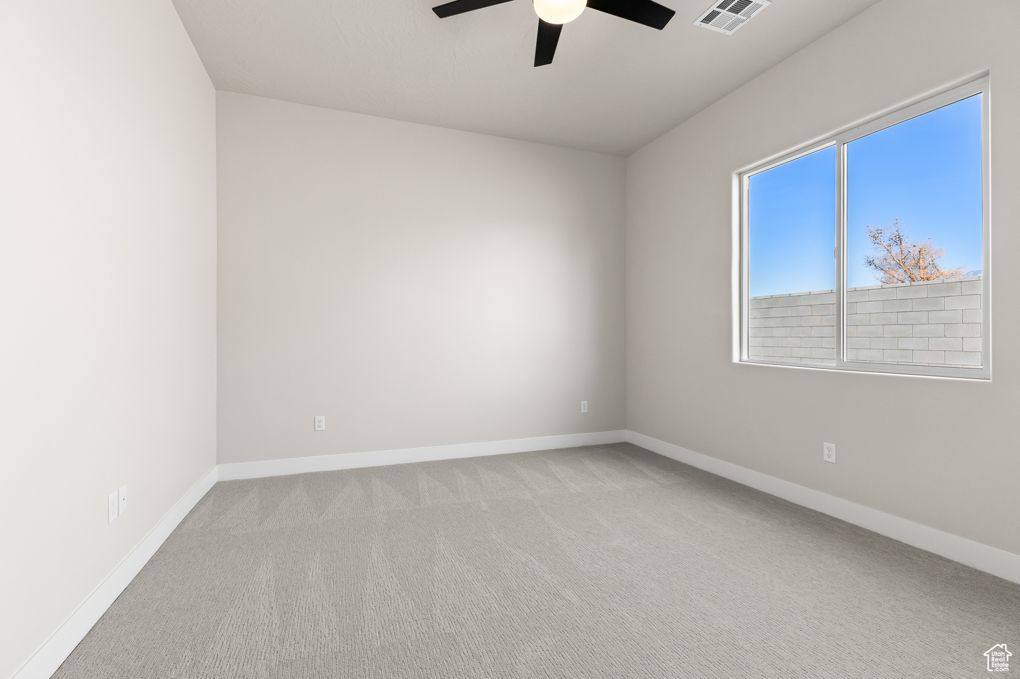 Spare room with ceiling fan, baseboards, visible vents, and light carpet