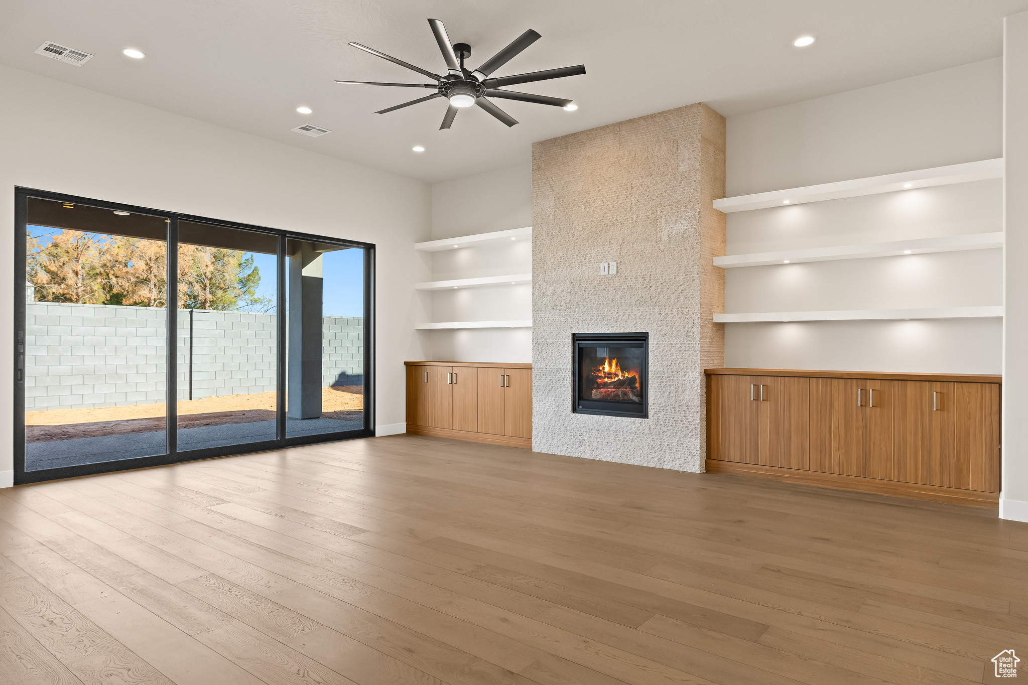 Unfurnished living room featuring a fireplace, recessed lighting, light wood-style floors, and visible vents