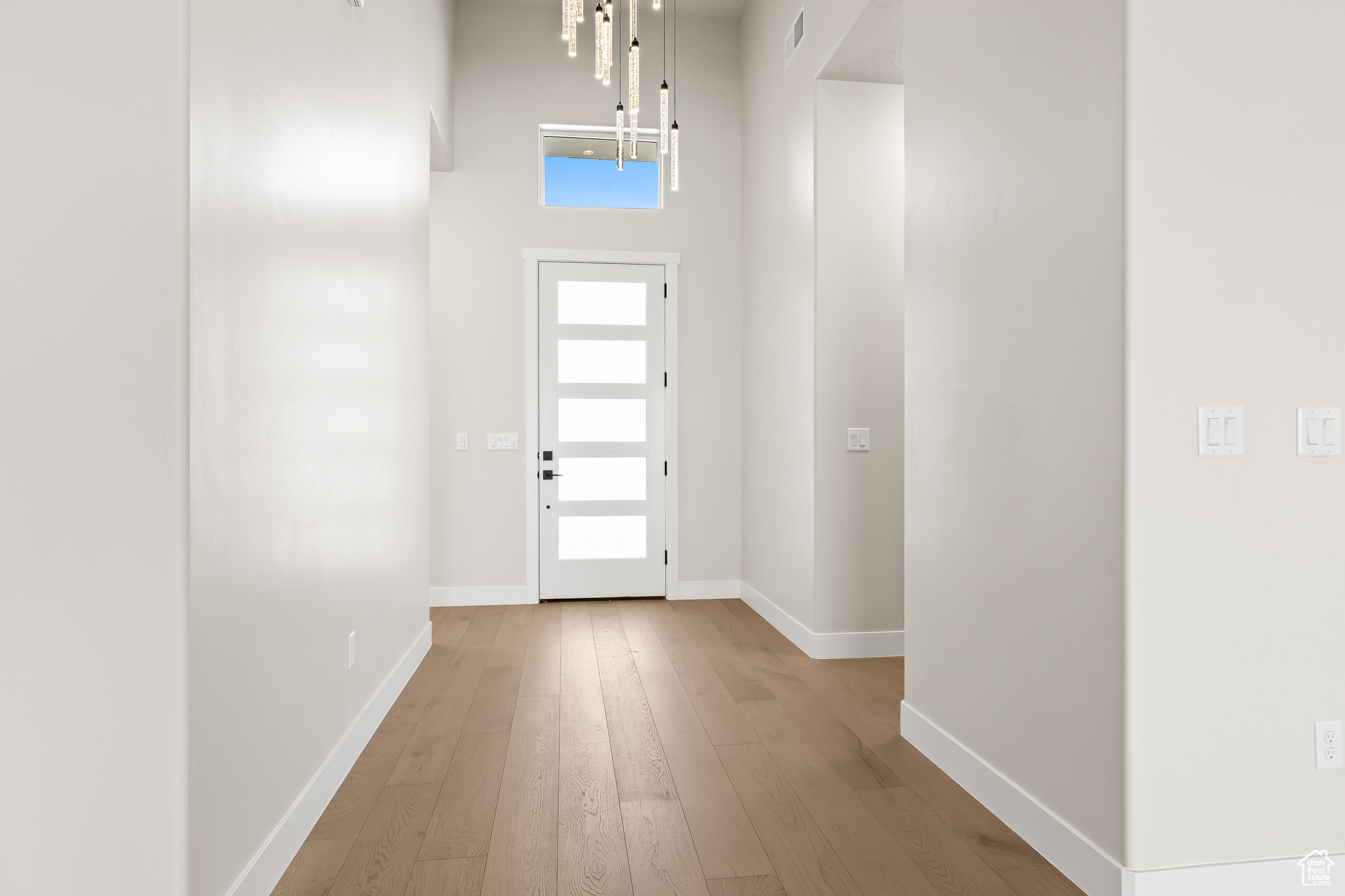 Entryway with visible vents, baseboards, a high ceiling, and hardwood / wood-style flooring