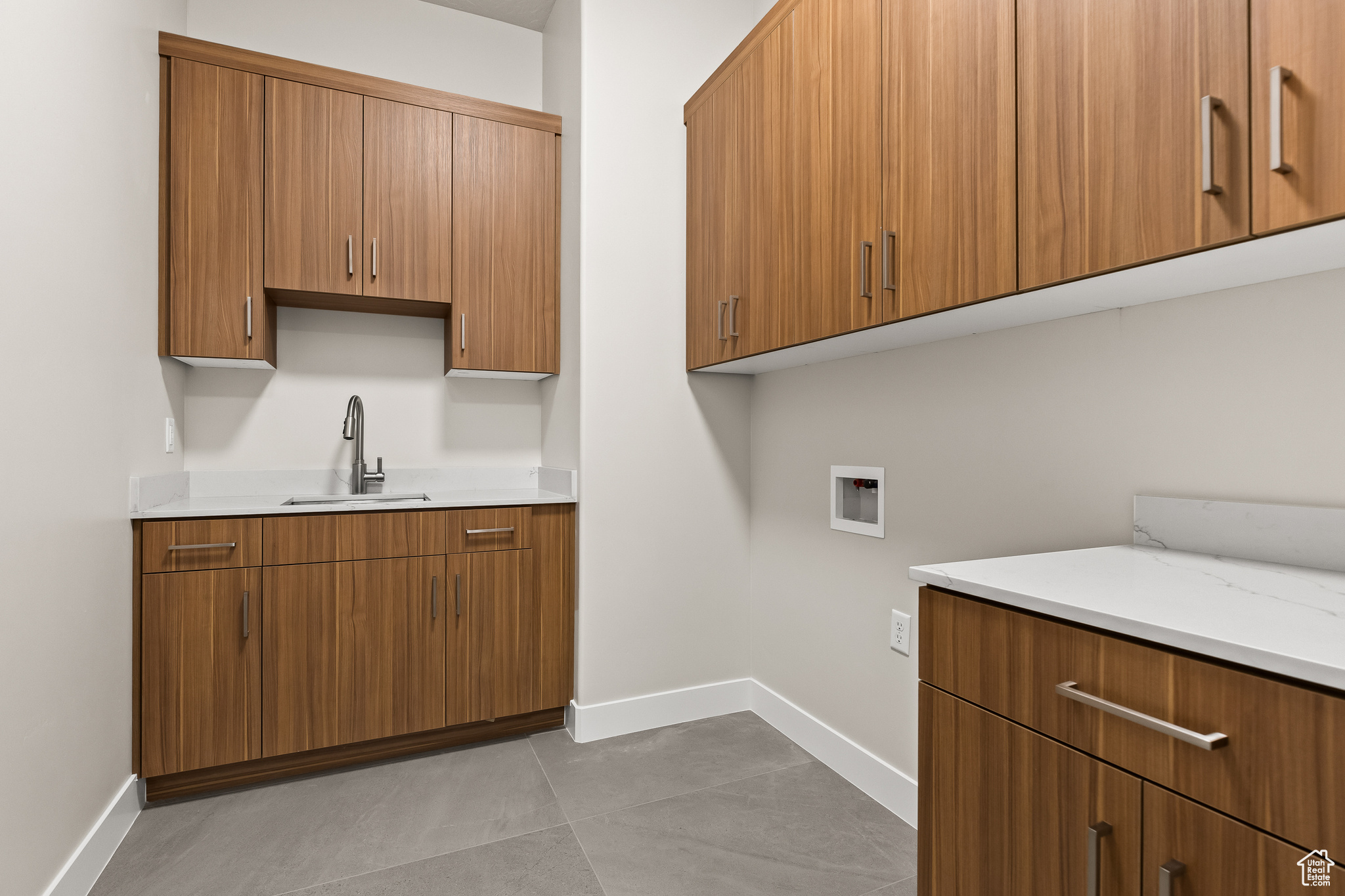 Washroom with hookup for a washing machine, cabinet space, baseboards, and a sink