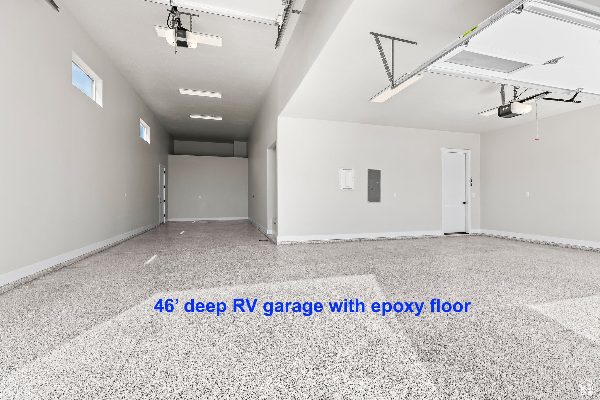 Garage with electric panel, a garage door opener, and baseboards