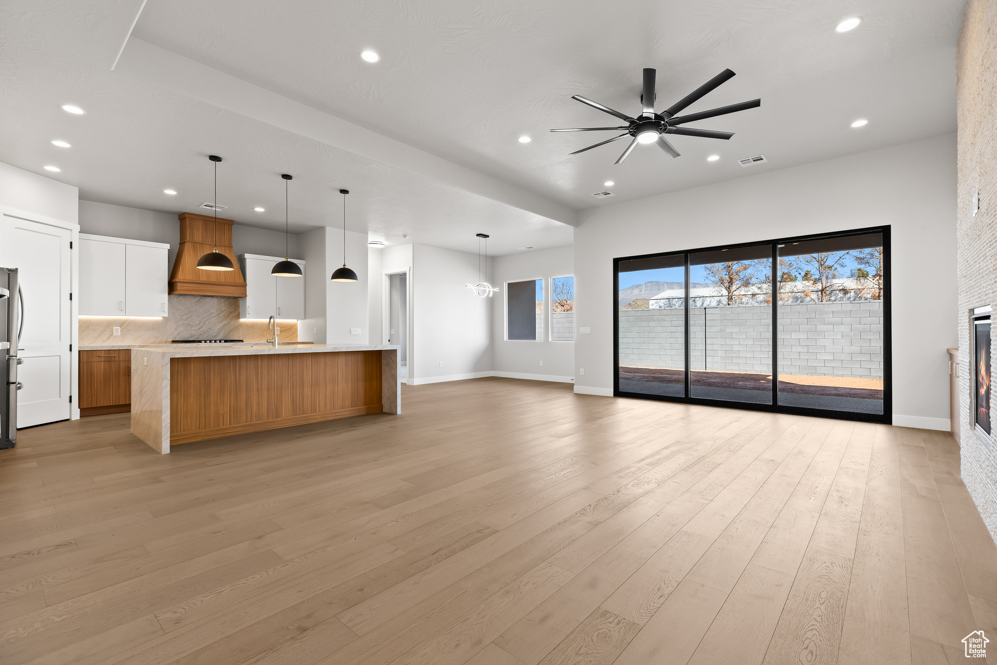 Unfurnished living room with visible vents, recessed lighting, light wood-style floors, a glass covered fireplace, and a sink