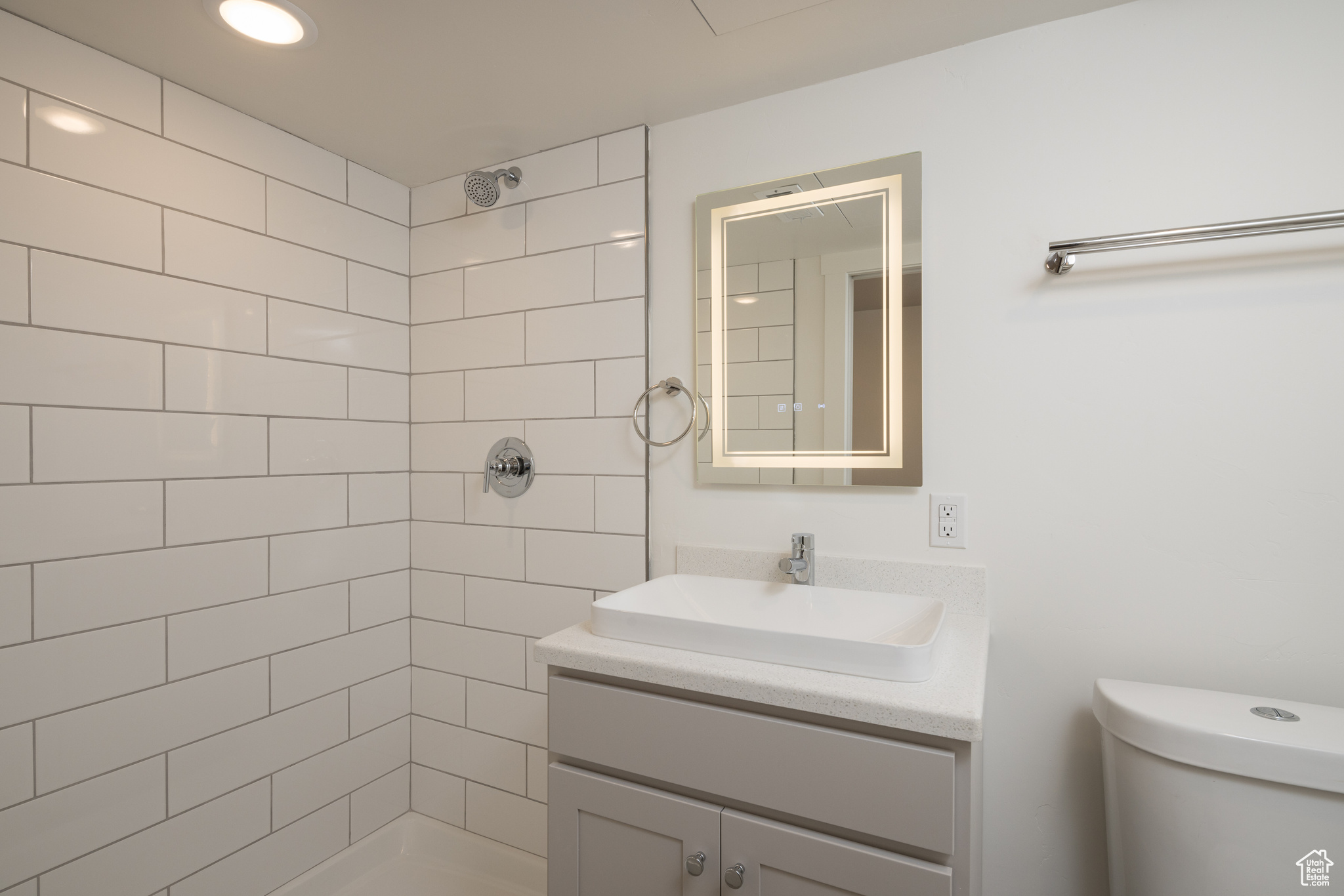 Bathroom with vanity, tiled shower, and toilet