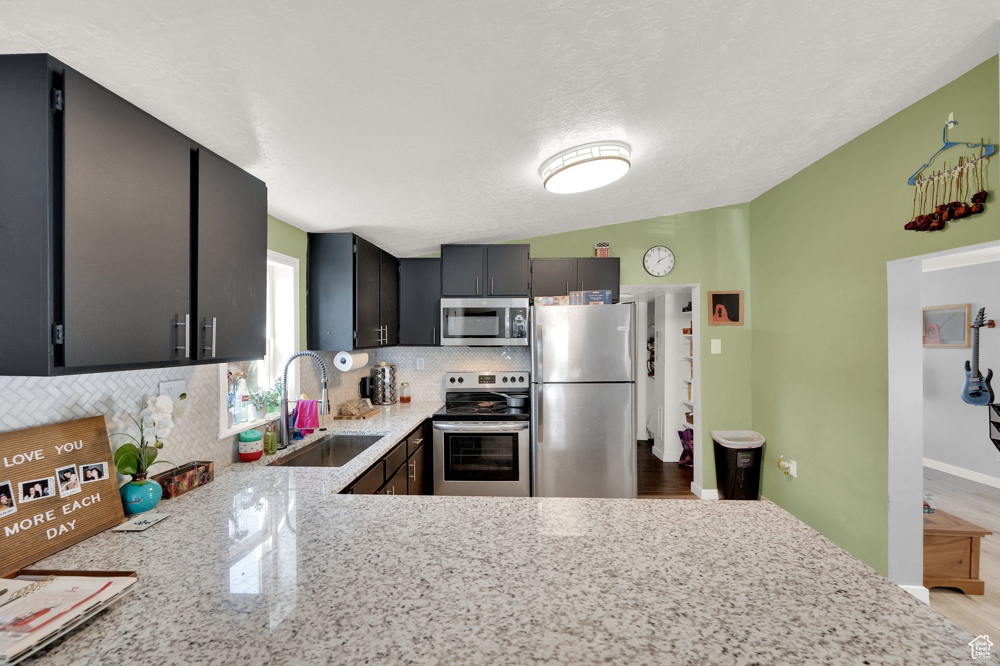 Kitchen featuring light stone counters, appliances with stainless steel finishes, sink, and backsplash
