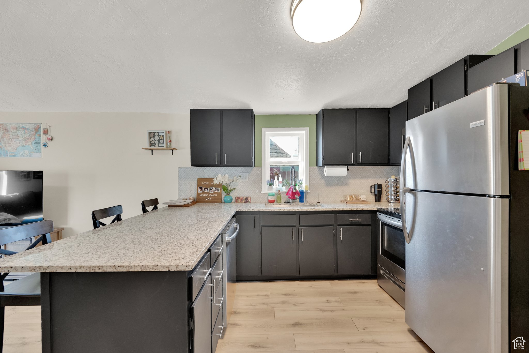 Kitchen with a kitchen bar, sink, kitchen peninsula, stainless steel appliances, and light hardwood / wood-style floors