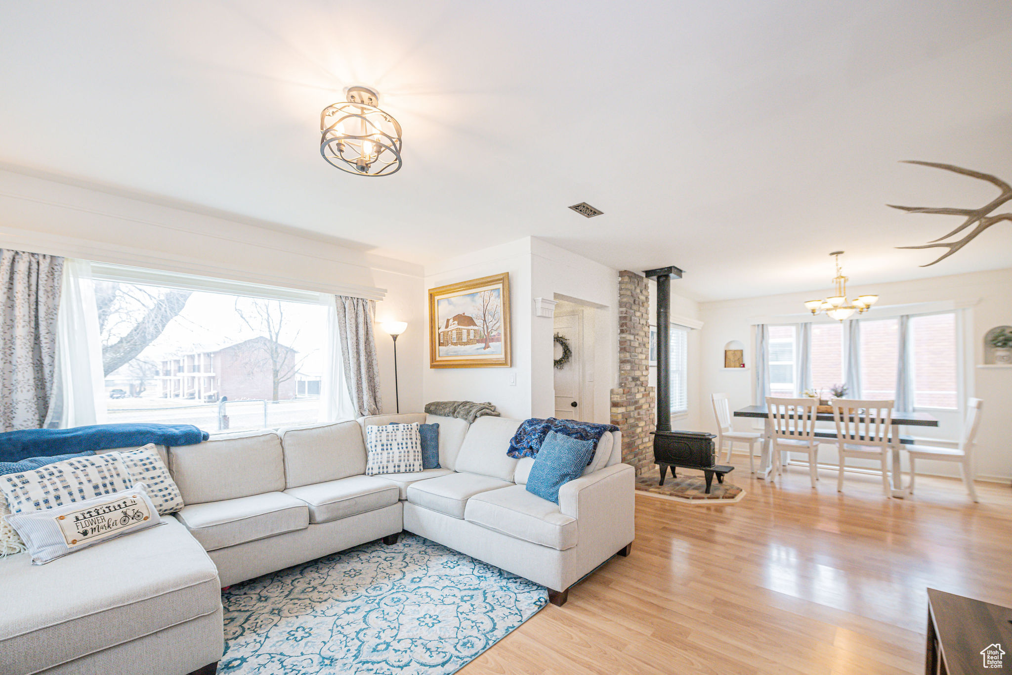 Living room with a wood stove, an inviting chandelier, and light hardwood / wood-style flooring
