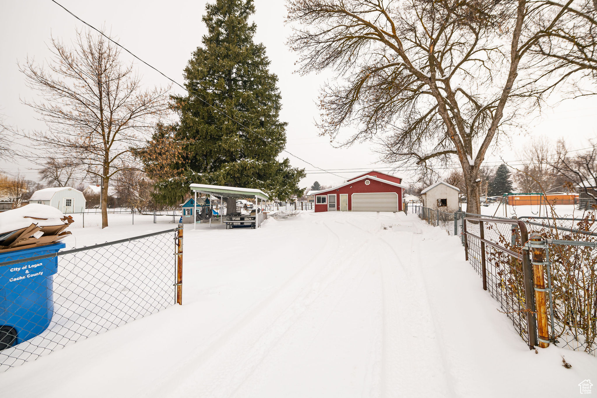 Yard layered in snow featuring an outbuilding and a garage
