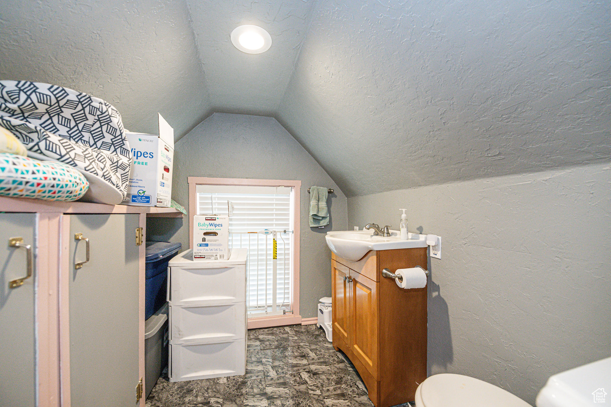 Bathroom with vanity, lofted ceiling, a textured ceiling, and toilet
