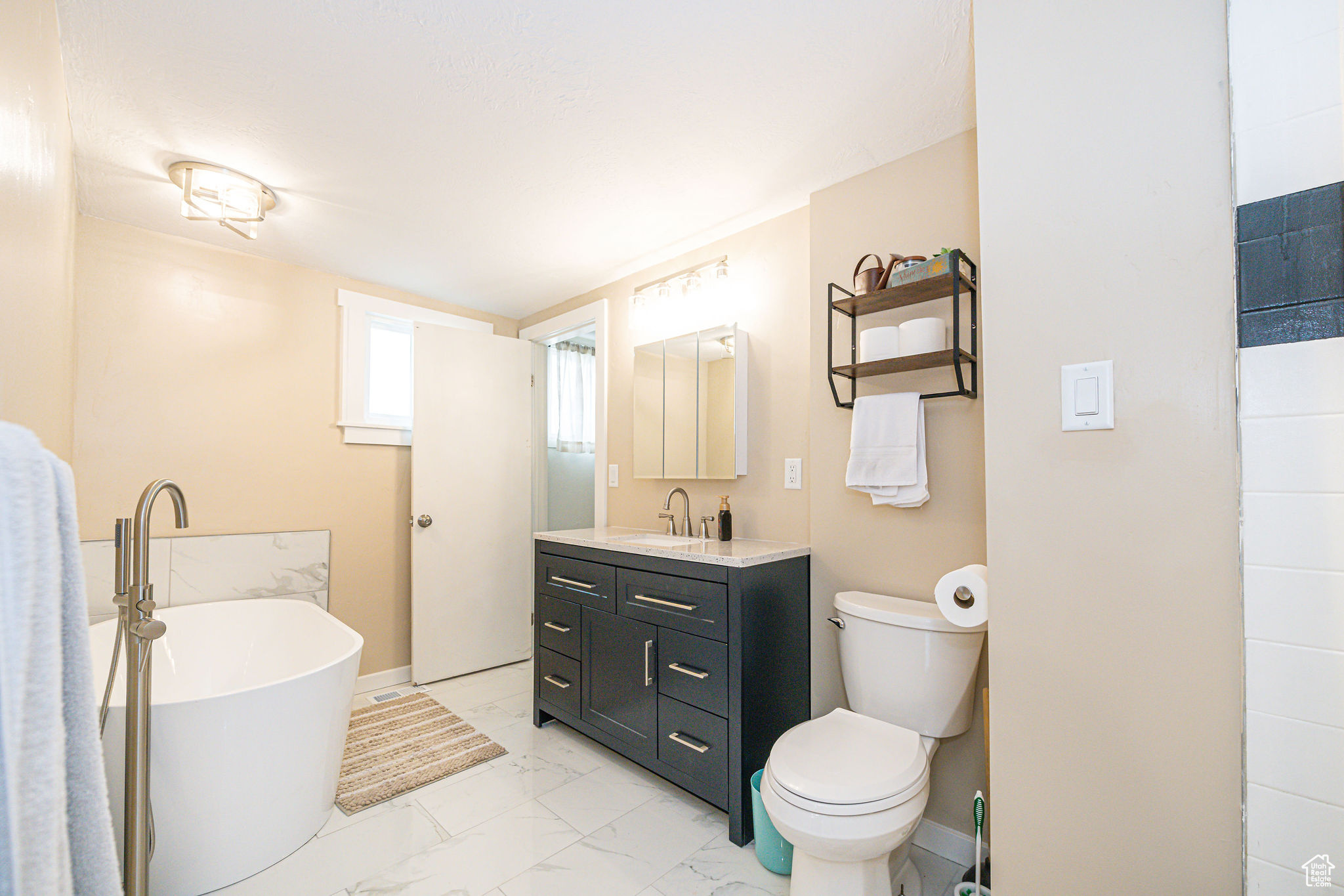 Bathroom featuring vanity, a washtub, and toilet