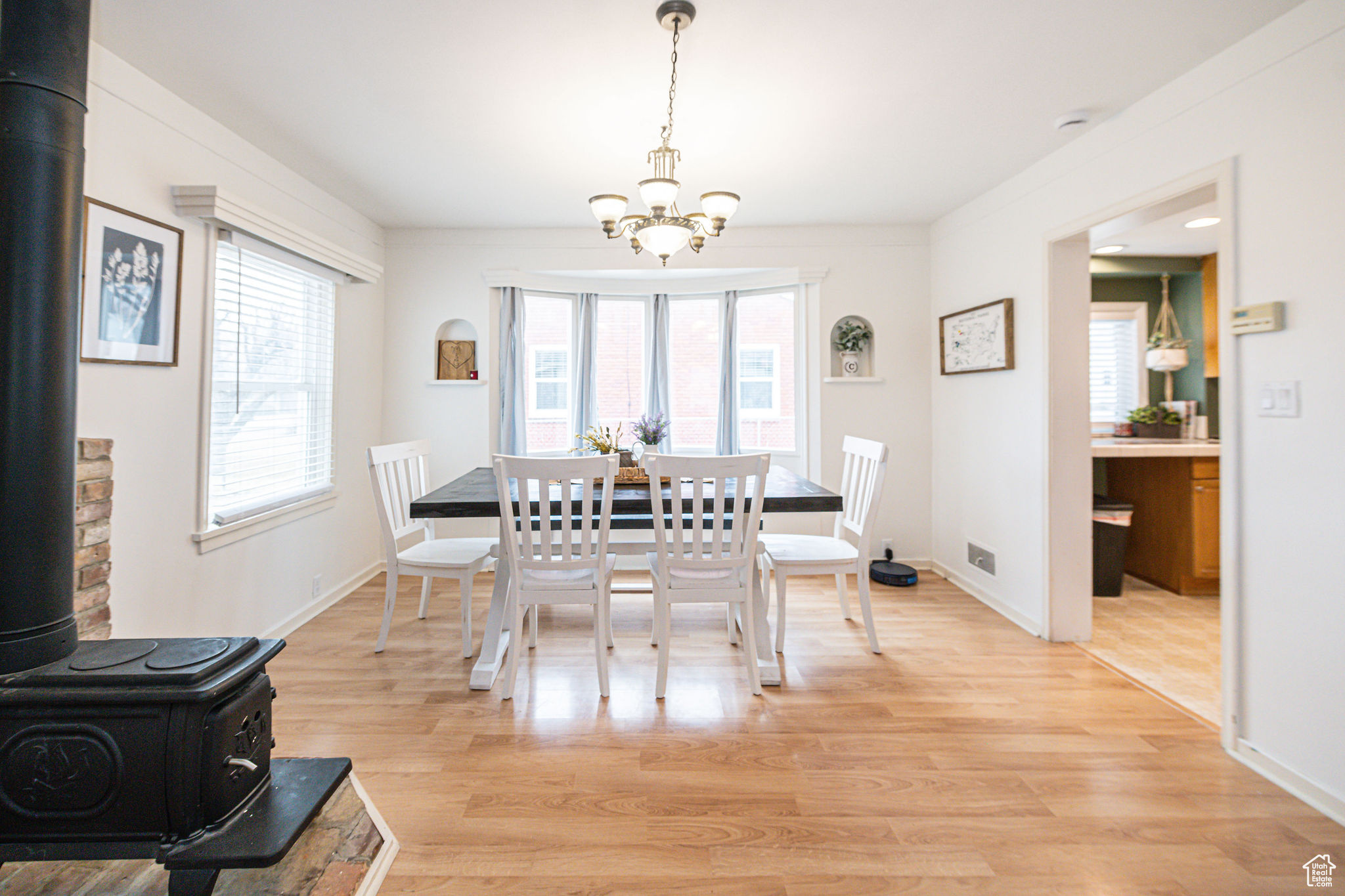 Dining area with a notable chandelier, light wood-type flooring, and a wood stove