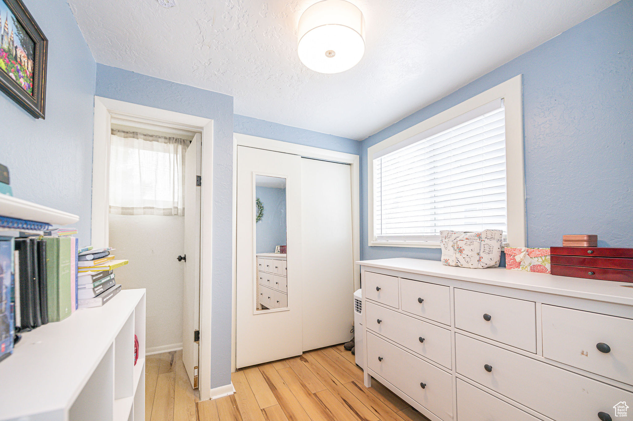 Bedroom with a closet, a textured ceiling, and light hardwood / wood-style flooring