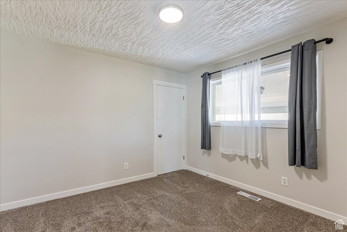 Carpeted empty room featuring a textured ceiling