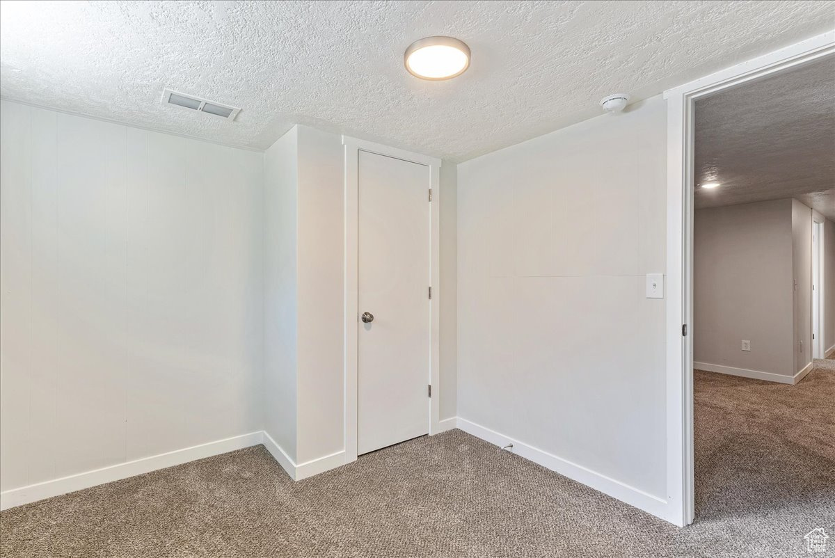 Unfurnished room featuring carpet and a textured ceiling