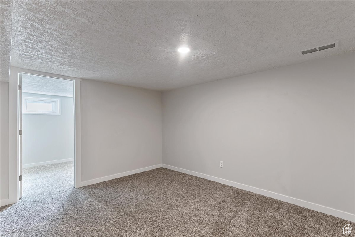 Empty room with carpet and a textured ceiling
