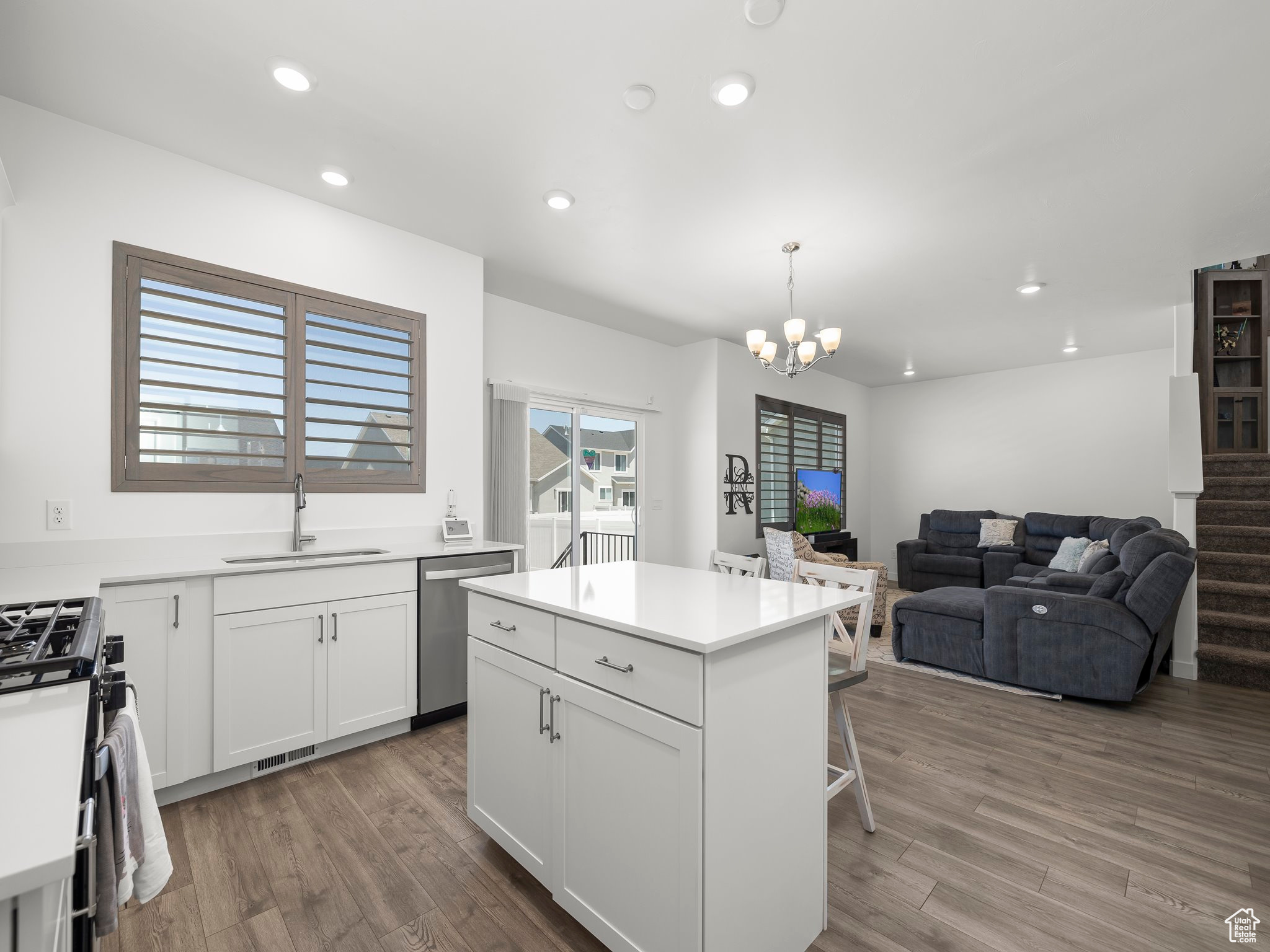 Kitchen featuring pendant lighting, sink, white cabinetry, stainless steel appliances, and a center island