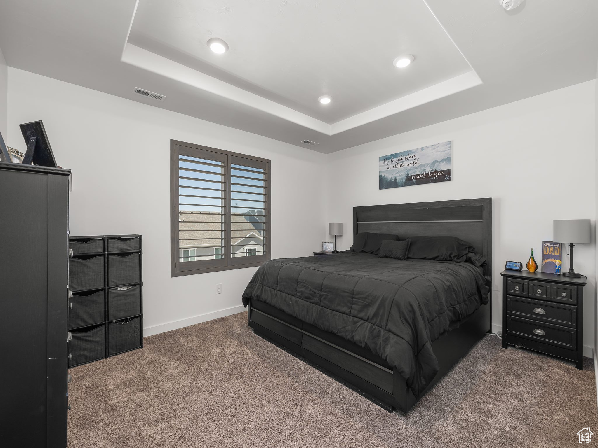Carpeted bedroom with a tray ceiling