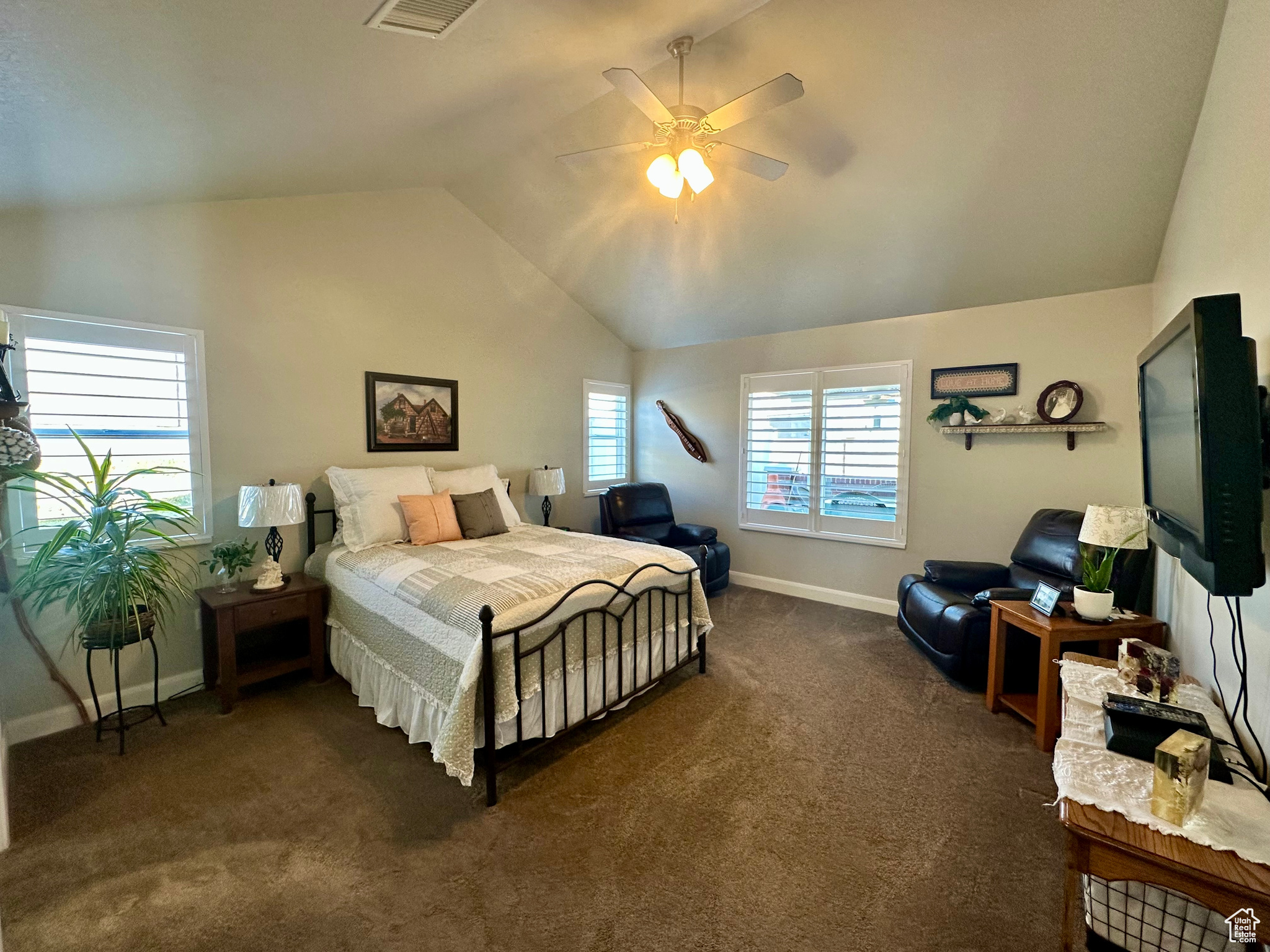 Bedroom with lofted ceiling, visible vents, dark carpet, a ceiling fan, and baseboards