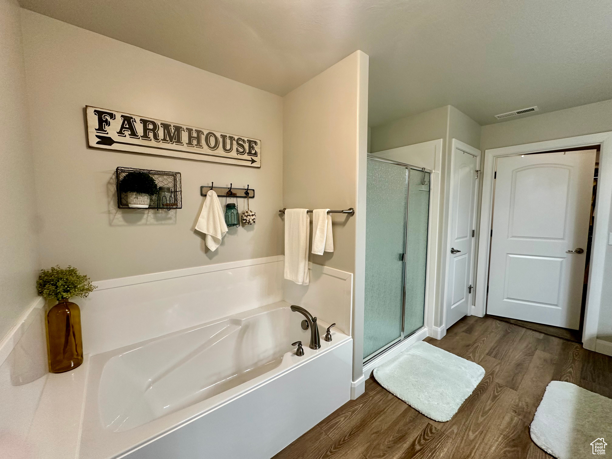 Full bath with a stall shower, visible vents, a garden tub, and wood finished floors