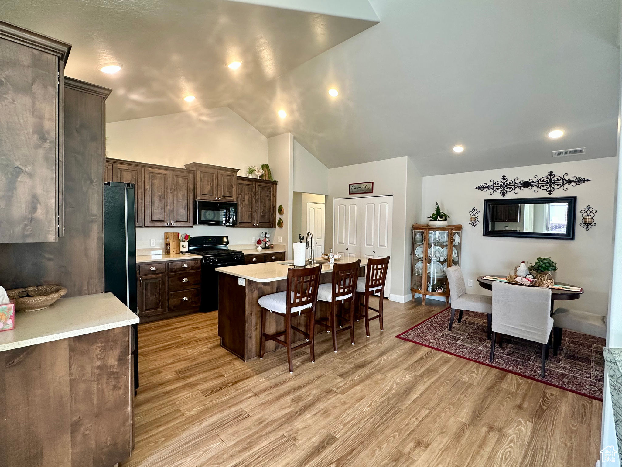 Kitchen with black appliances, light wood-style flooring, visible vents, and light countertops
