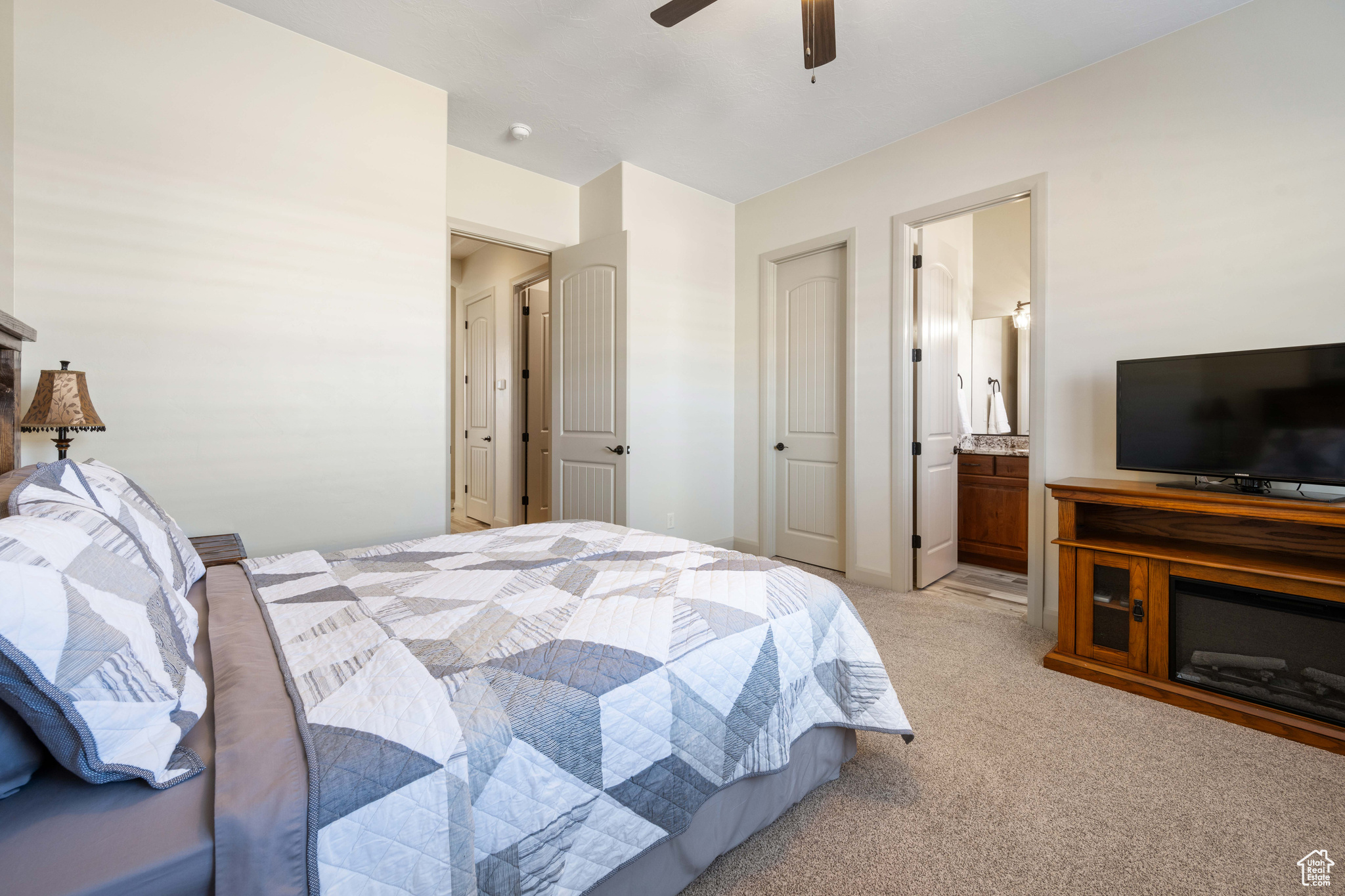 Bedroom with light carpet, connected bathroom, and ceiling fan
