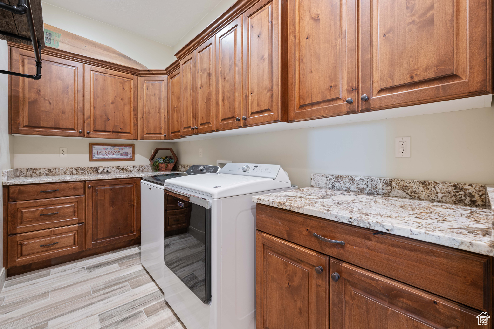 Laundry area with cabinets, washing machine and dryer, and light wood-type flooring