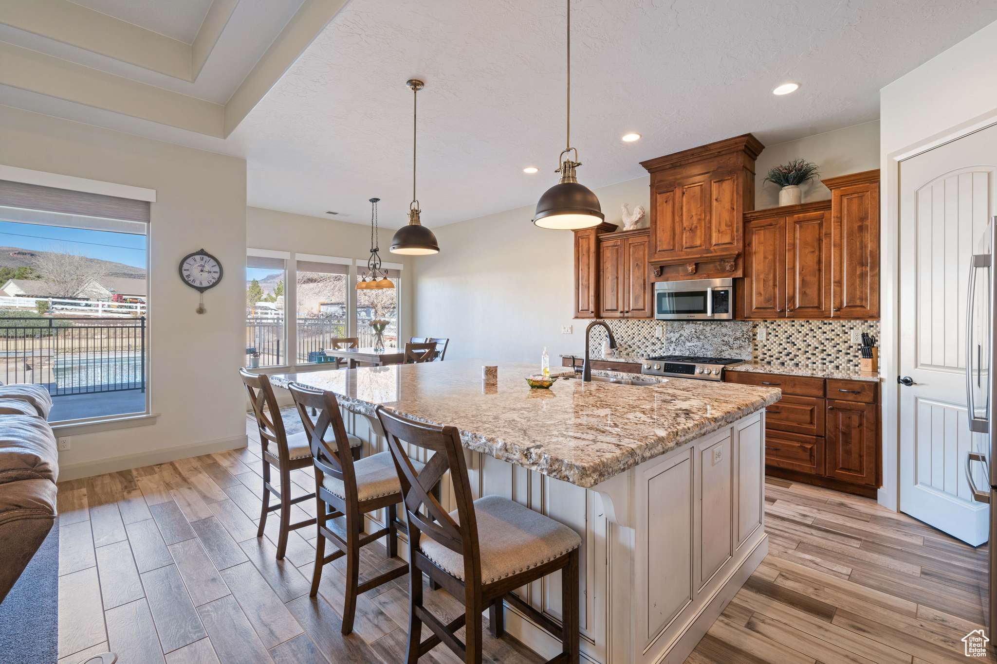 Kitchen featuring sink, tasteful backsplash, hanging light fixtures, a kitchen breakfast bar, and an island with sink
