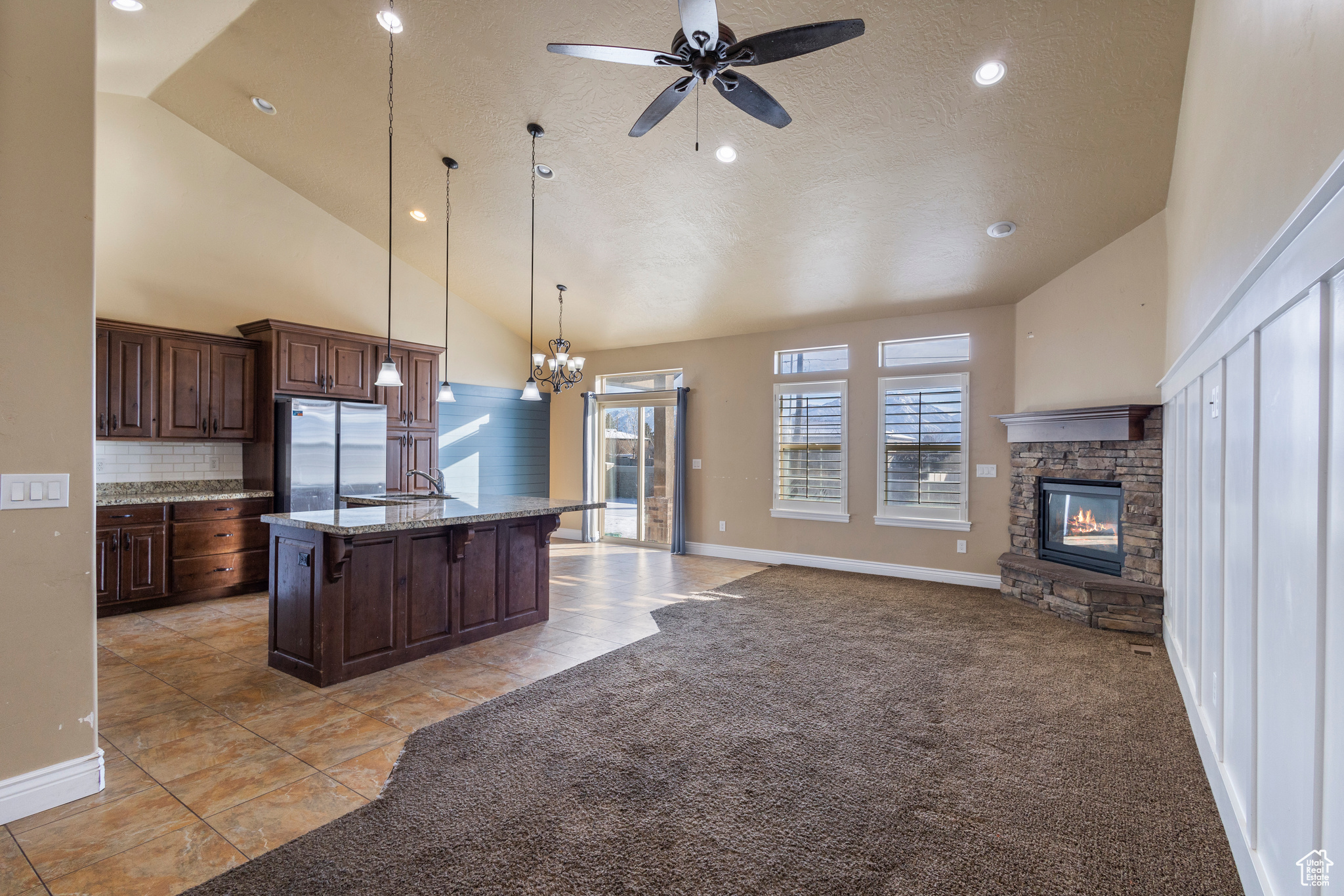 Kitchen featuring pendant lighting, stainless steel refrigerator, a kitchen island with sink, a kitchen breakfast bar, and light colored carpet