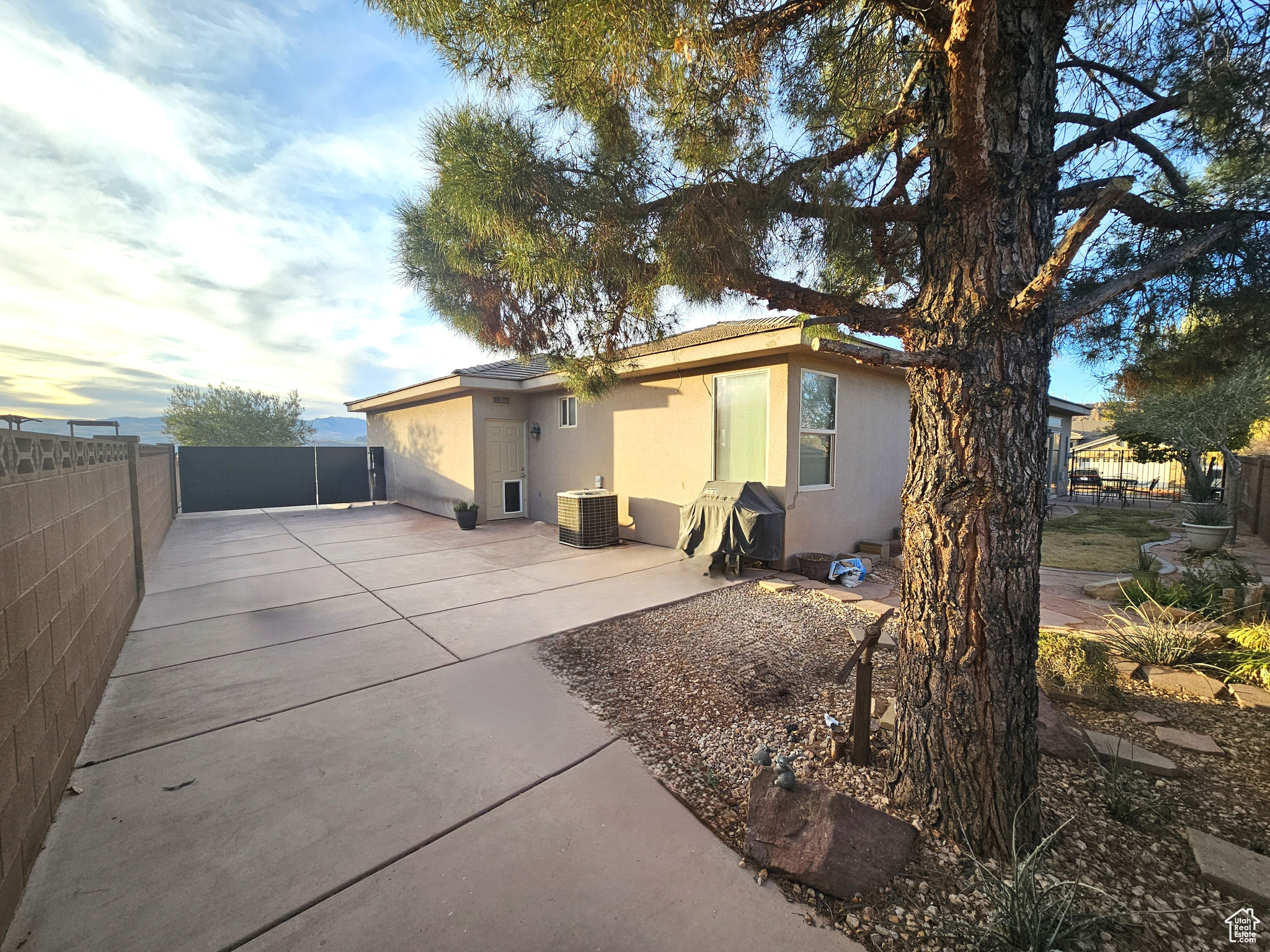 Back house at dusk featuring cooling unit and a patio area