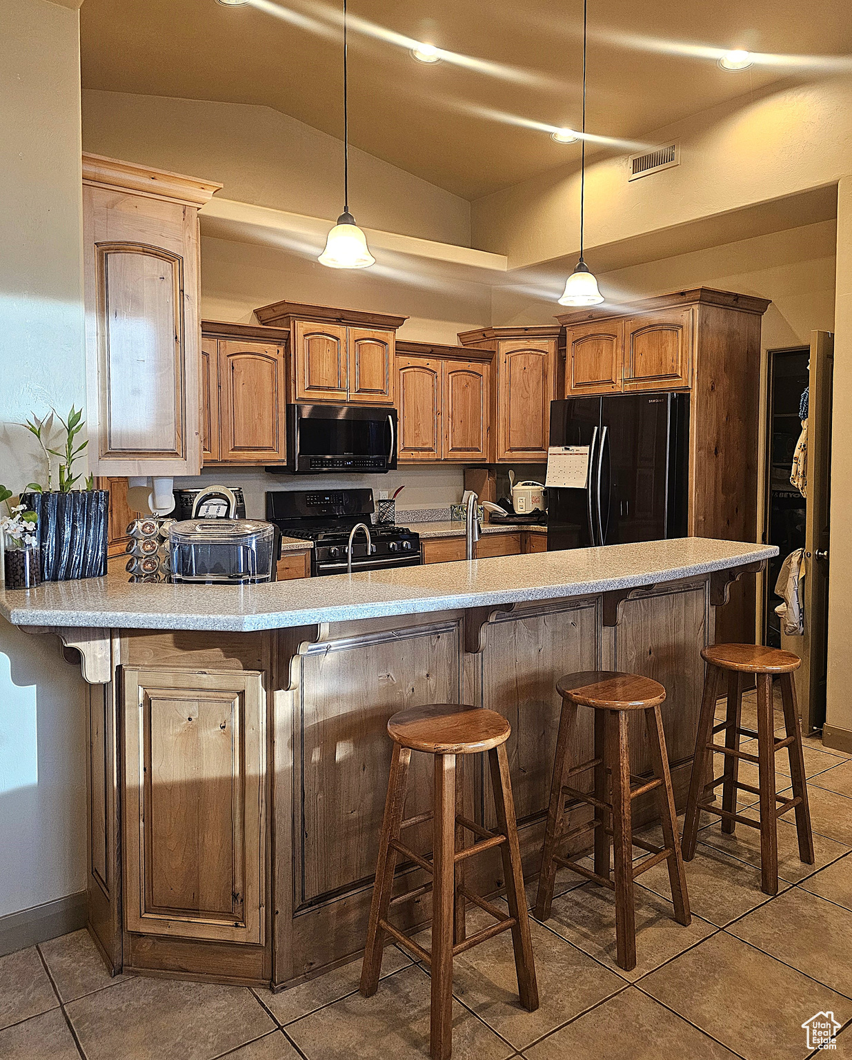 Kitchen with pendant lighting, a breakfast bar area, and black appliances