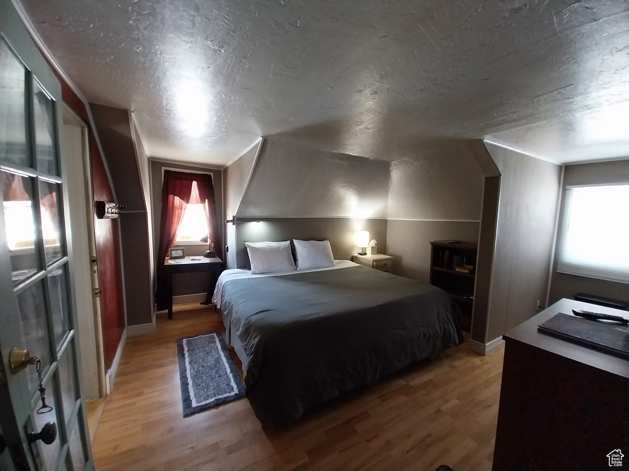 Bedroom featuring lofted ceiling, a textured ceiling, and light wood-type flooring