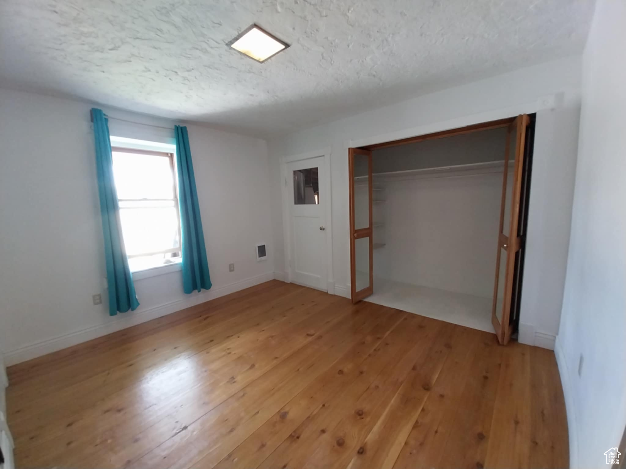 Unfurnished bedroom with a closet, a textured ceiling, and light hardwood / wood-style flooring
