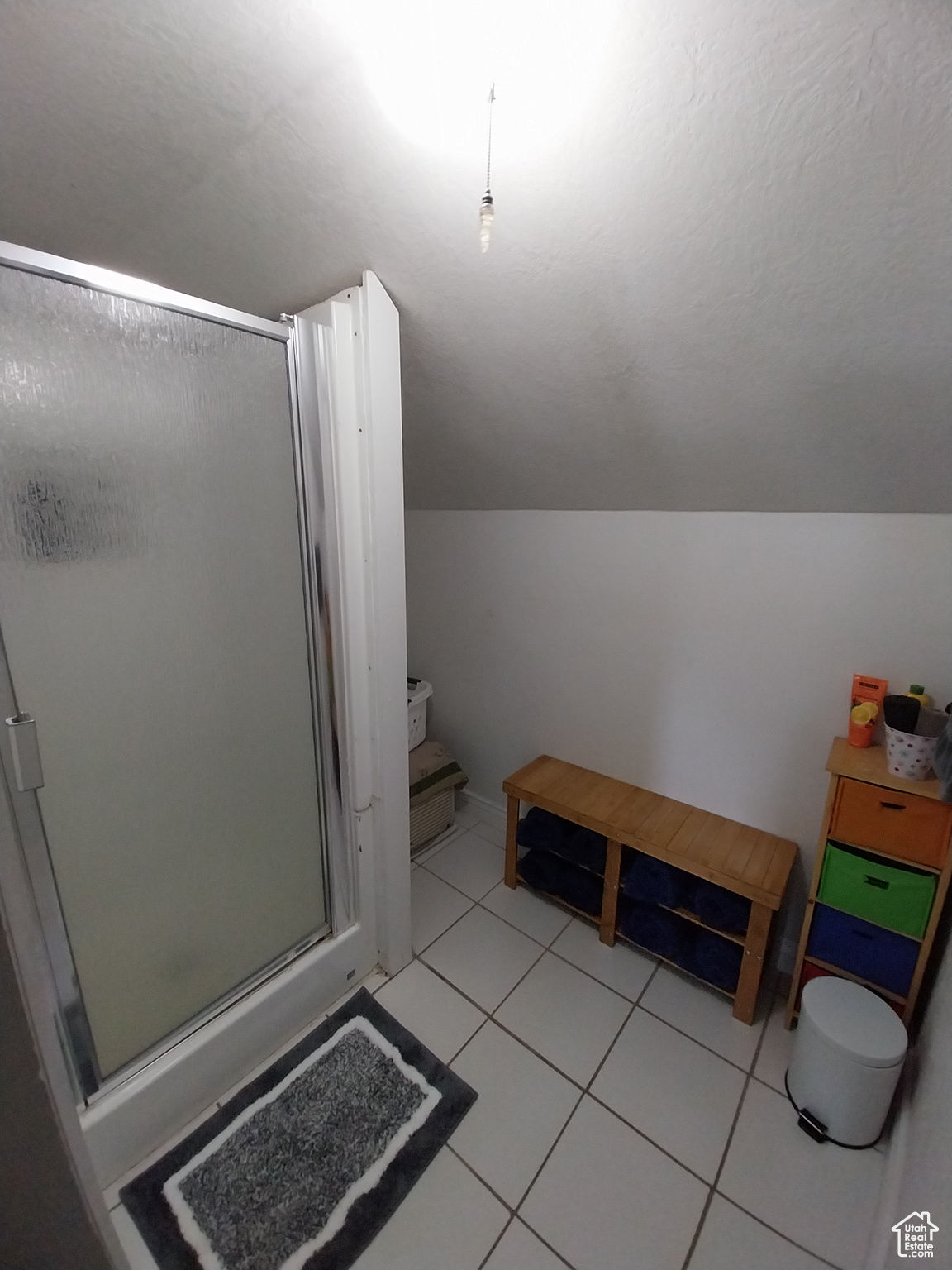 Bathroom with lofted ceiling, tile patterned floors, and walk in shower