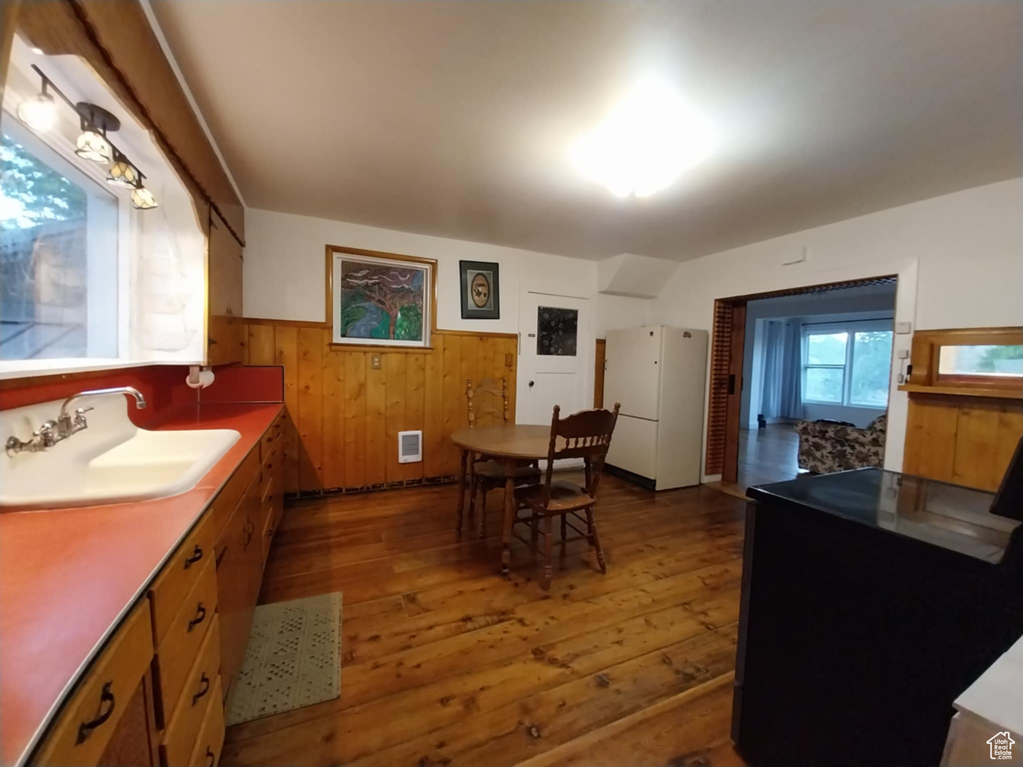 Kitchen with sink, stove, hardwood / wood-style floors, white fridge, and wood walls