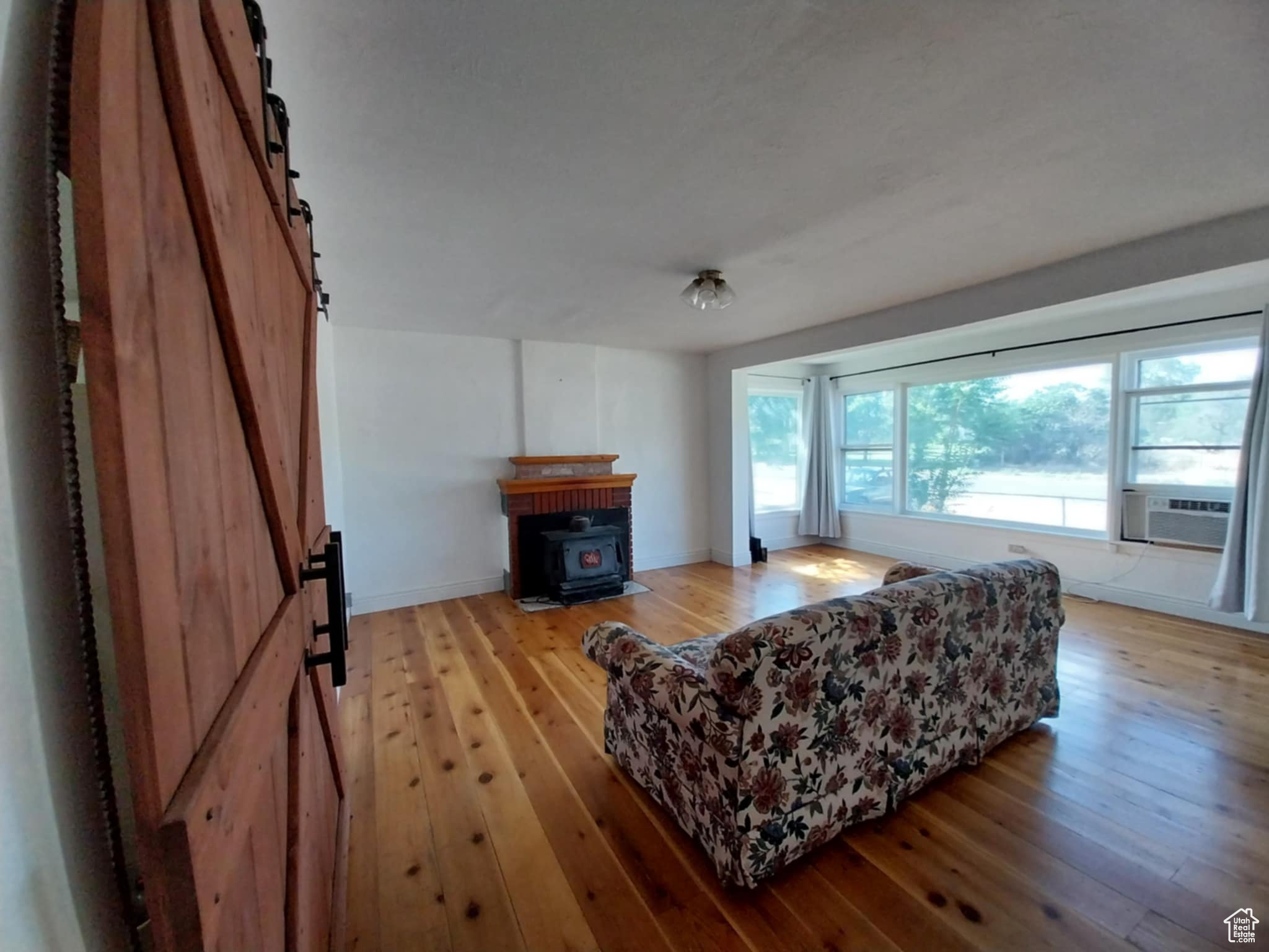 Living room with a barn door, cooling unit, and light wood-type flooring