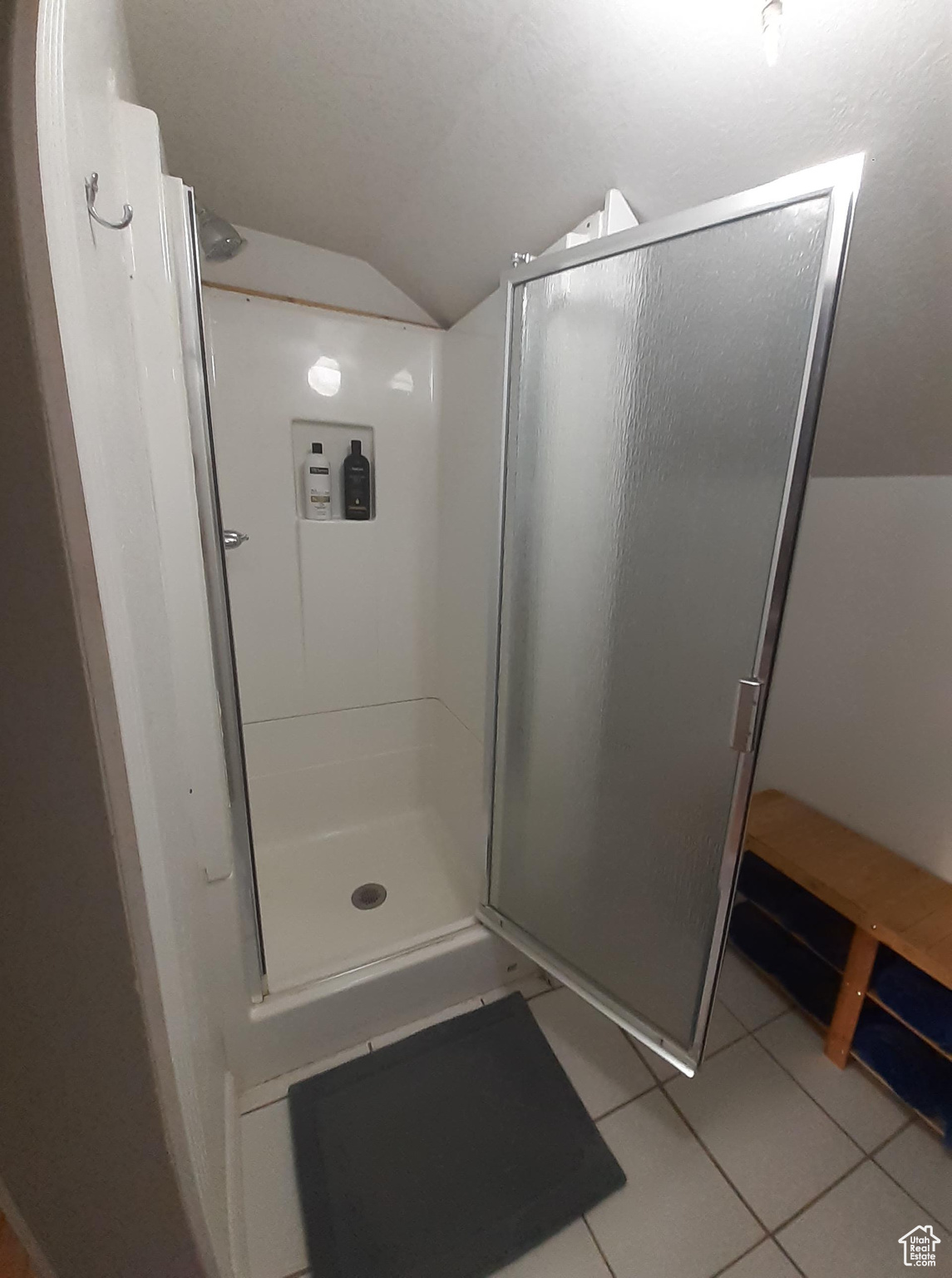 Bathroom with lofted ceiling, tile patterned floors, and a shower with door