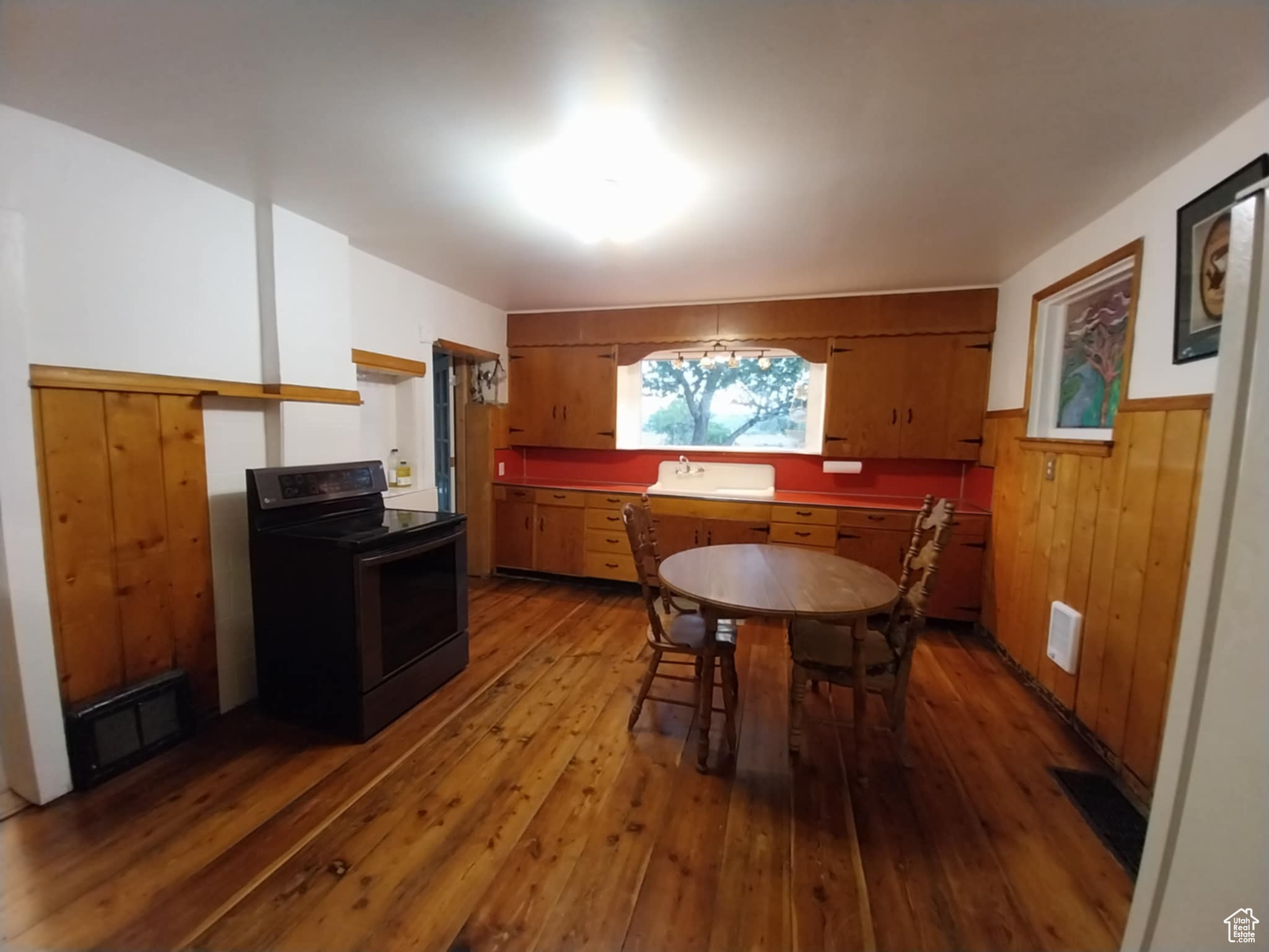 Dining space featuring wooden walls, sink, and light wood-type flooring