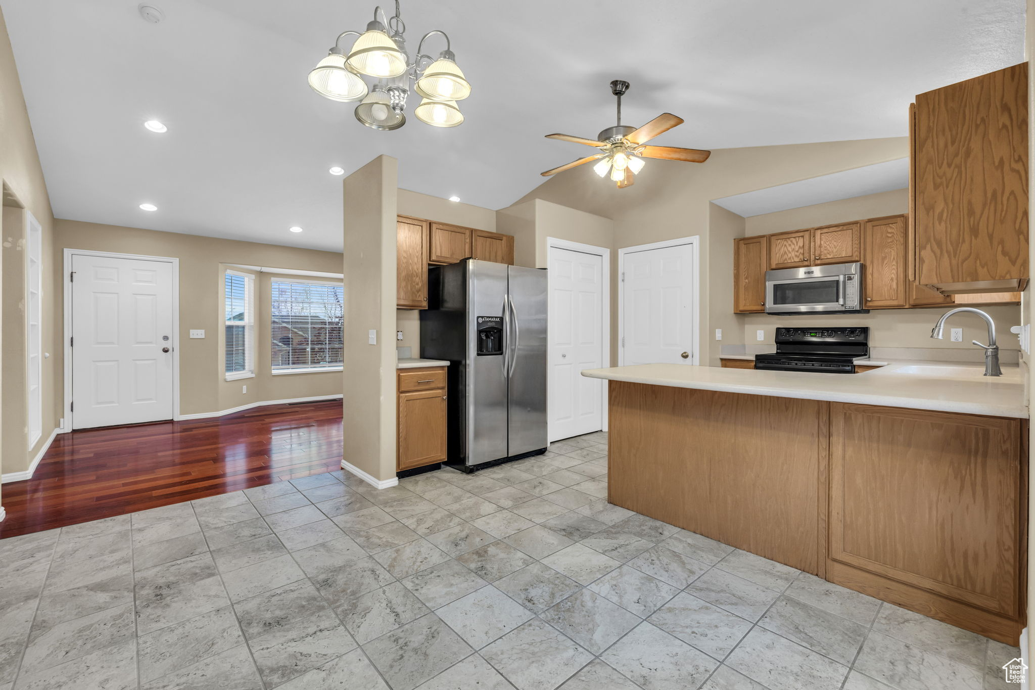 Kitchen featuring appliances with stainless steel finishes, pendant lighting, lofted ceiling, sink, and kitchen peninsula