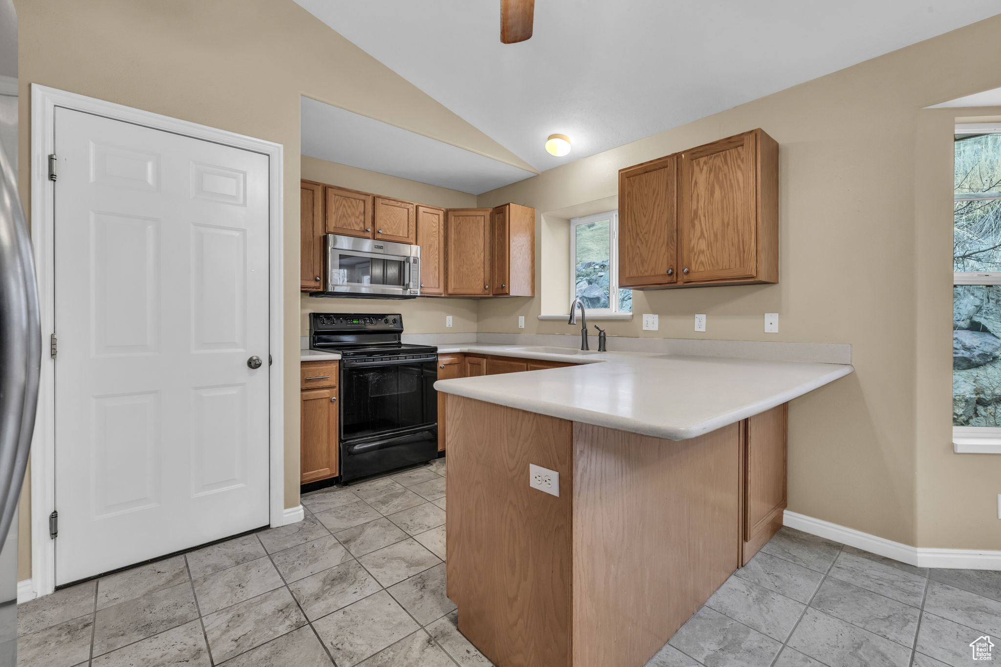 Kitchen featuring lofted ceiling, sink, kitchen peninsula, ceiling fan, and black range with electric stovetop
